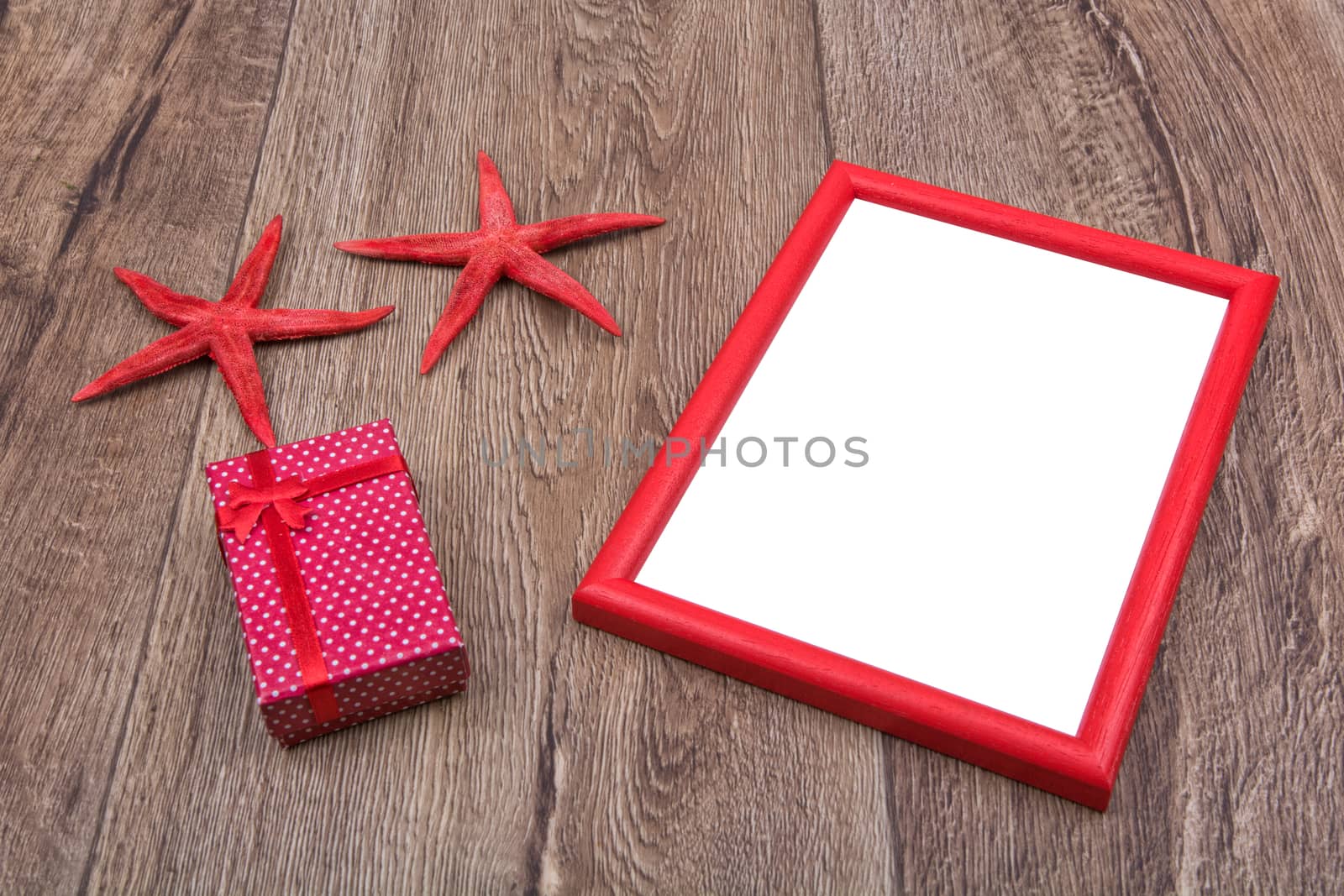 Red starfishes, gift and picture frame on a wooden background