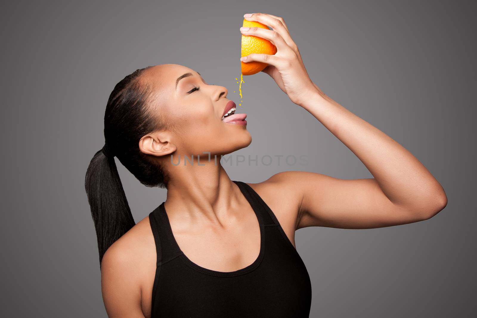 Happy healthy black asian woman squeezing orange juice fruit by phakimata