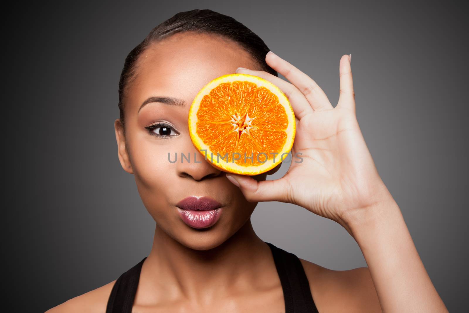 Happy healthy black asian woman with orange fruit by phakimata