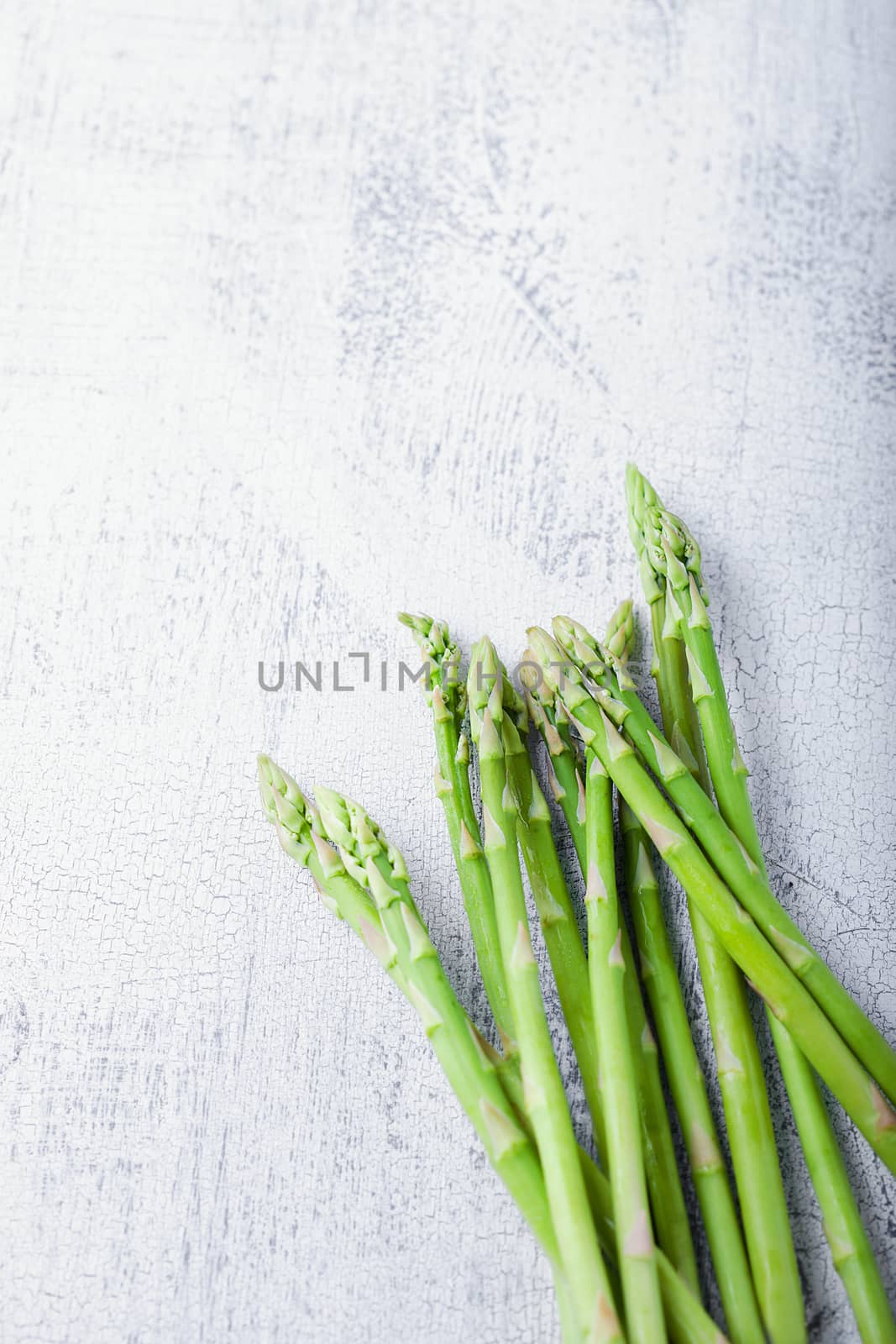 A bunch of green Fresh Asparagus on a white surface