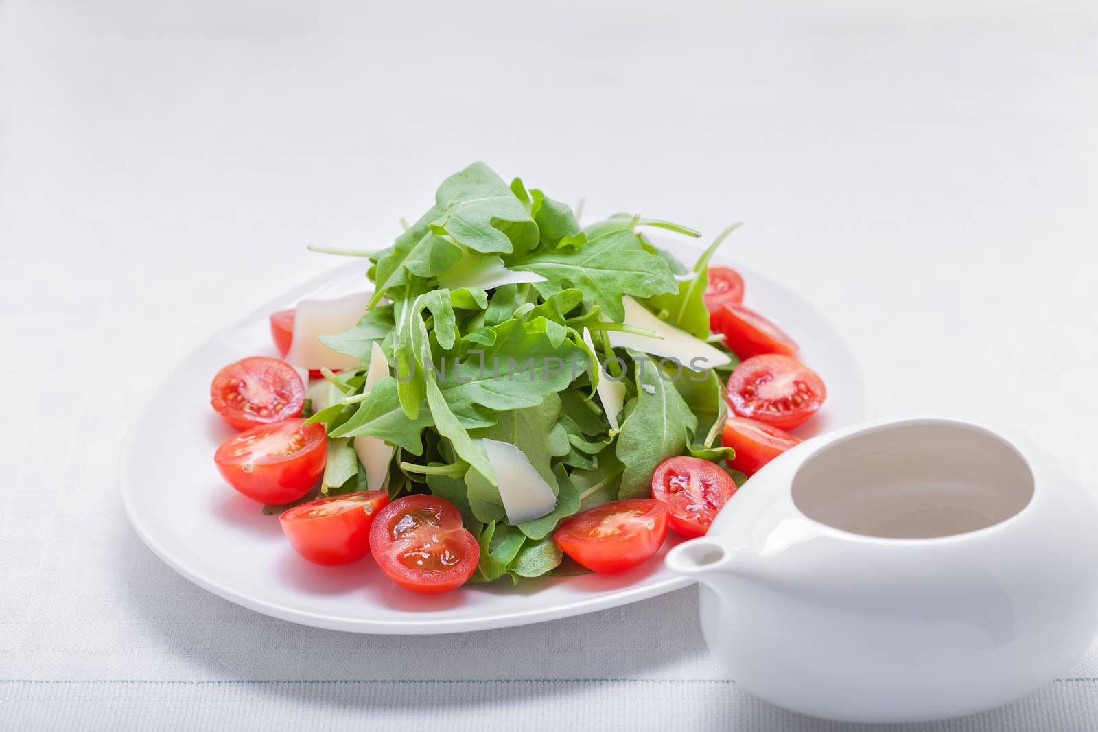 Salad with arugula, tomatoes and greenery on a plate
