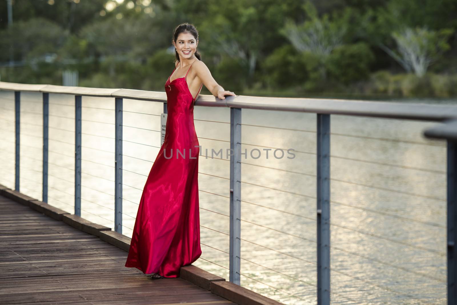 Beautiful young woman in the gardens wearing a long silk red dre by artistrobd