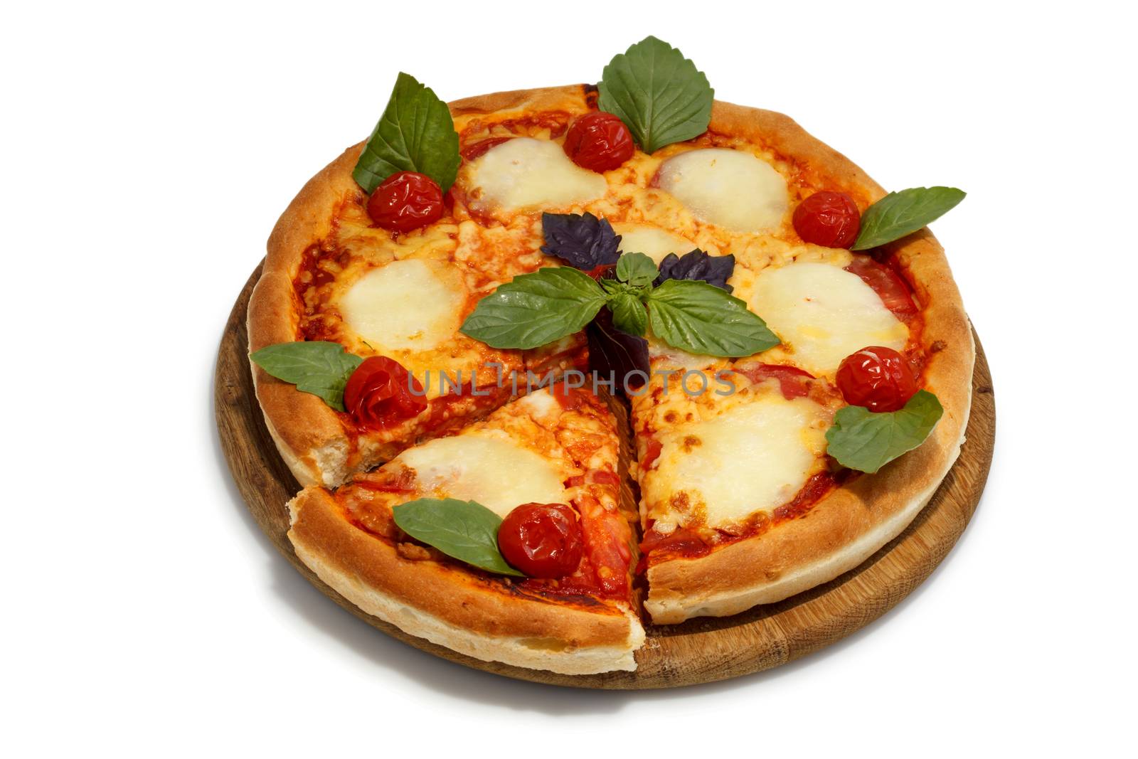 Pizza on a round wooden tray decorated with basil leaves