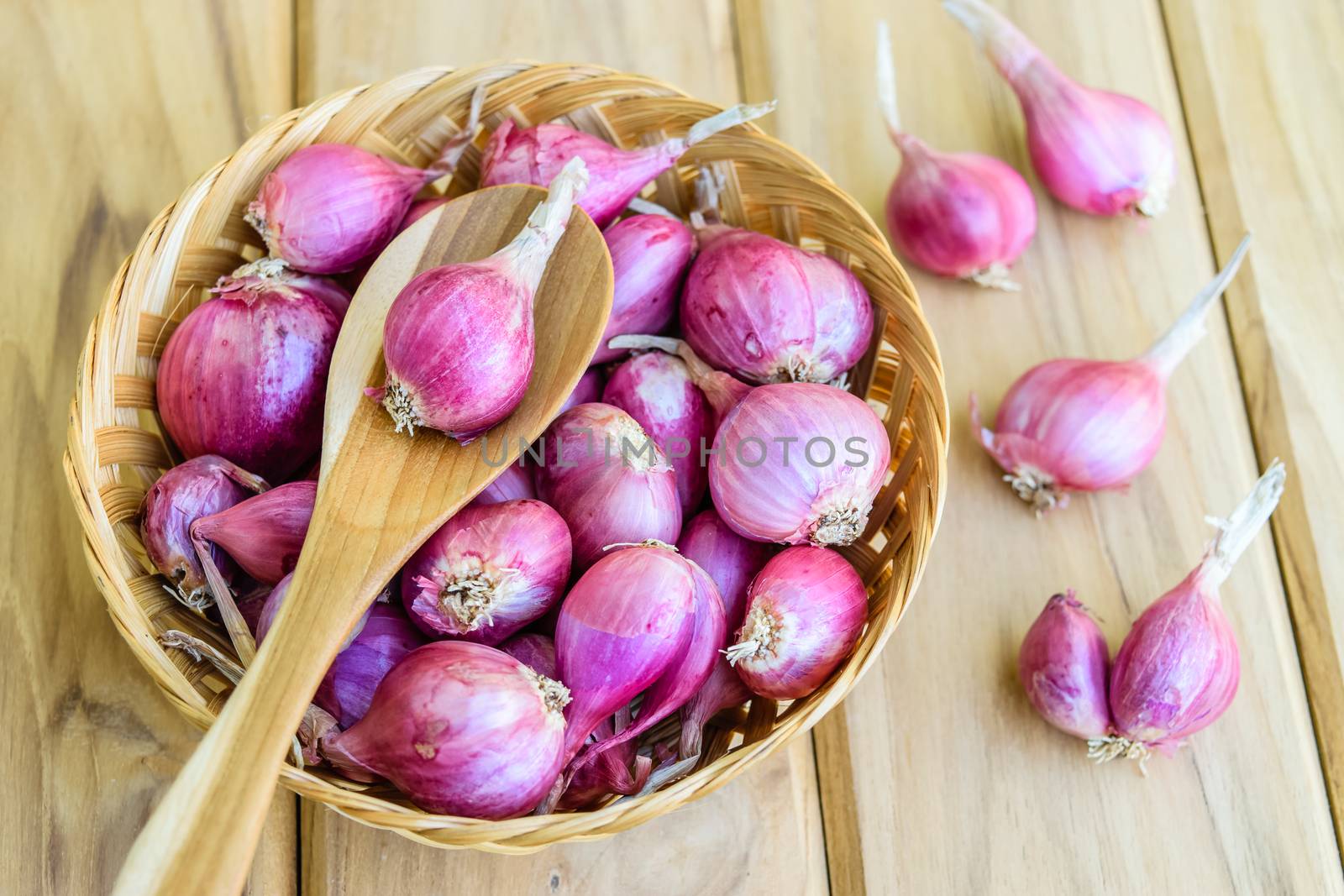 Shallot on wooden spoon and bamboo basket