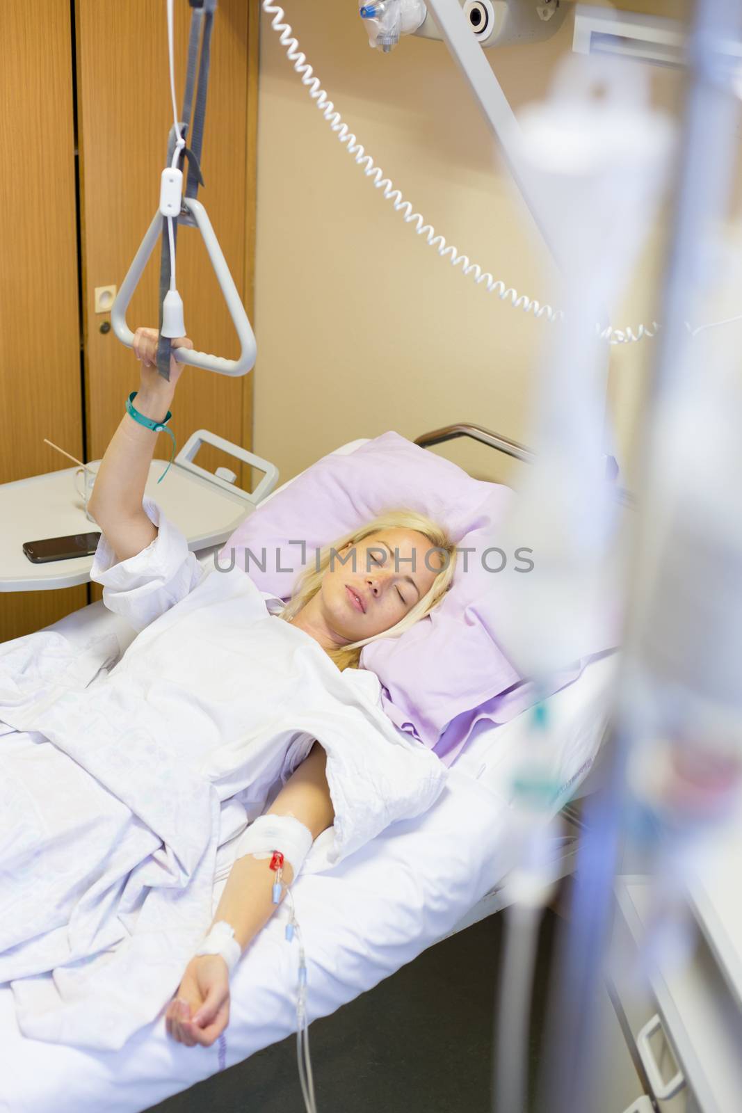 Bedridden female patient lying in hospital bed, recovering after surgery.