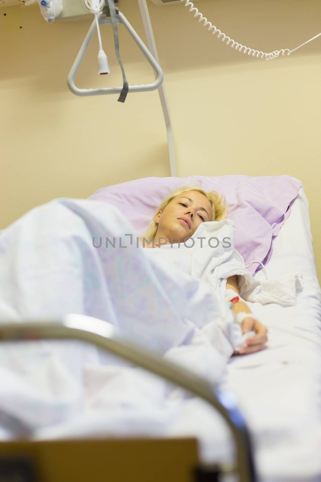 Bedridden female patient lying in hospital bed, recovering after surgery.