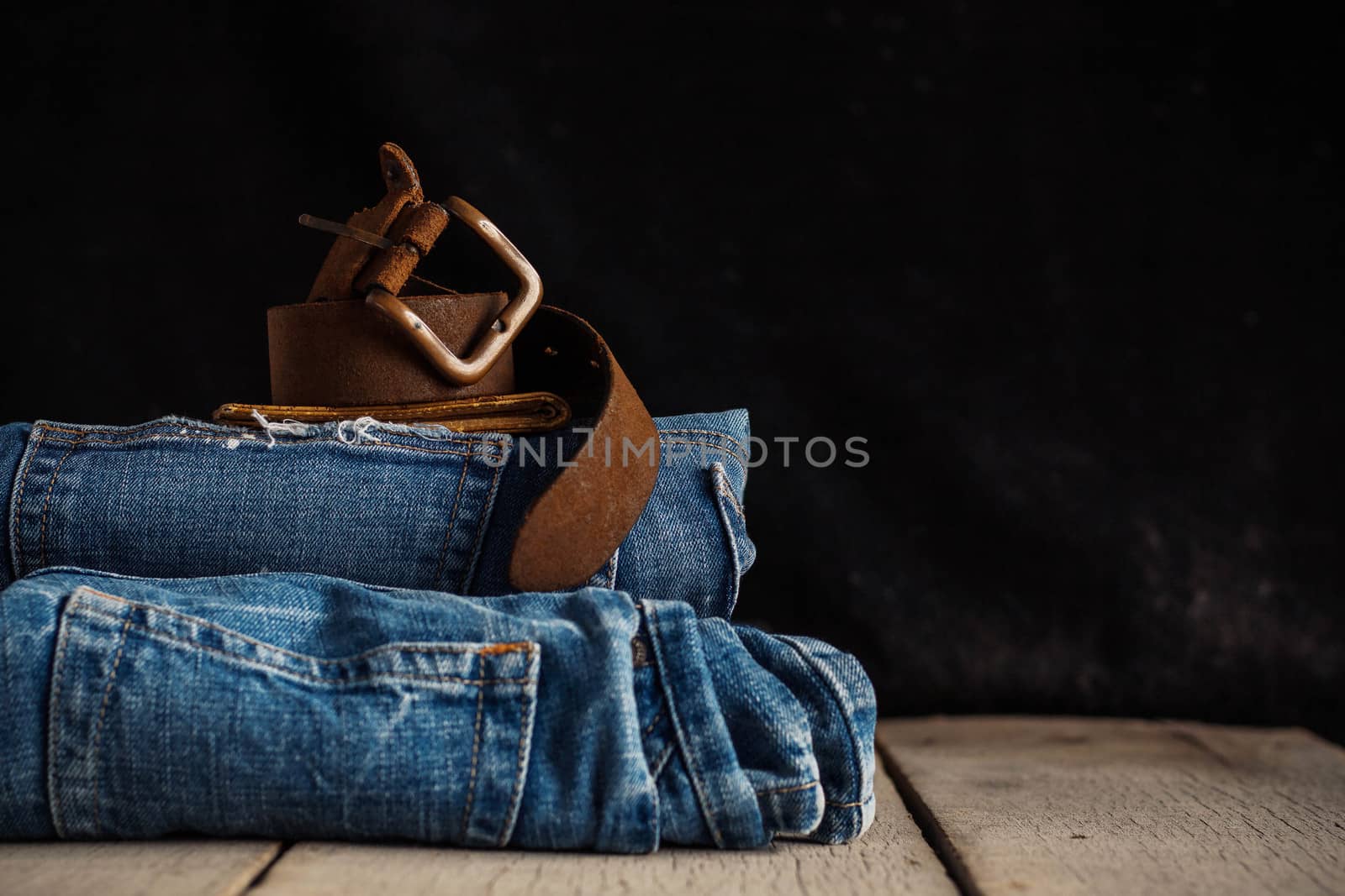 Old leather of belt and jeans on a wooden.