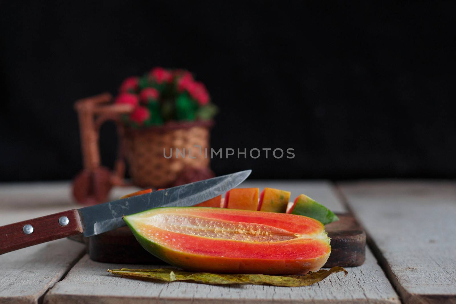 Papaya and a knife cut on the old wooden floor.