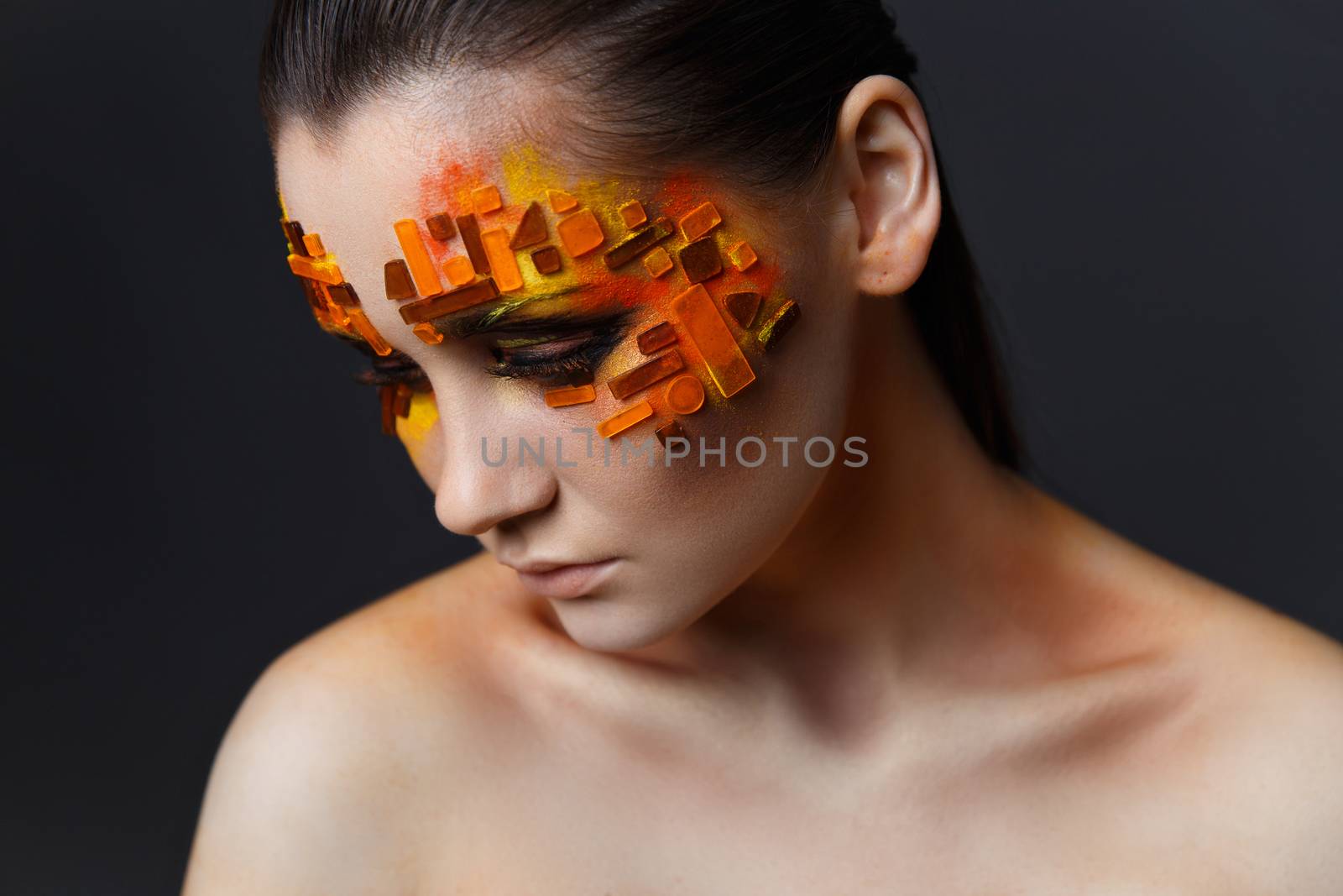 Portrait of a girl with an original make-up. Beauty close-up. Orange and red rhinestones on a face