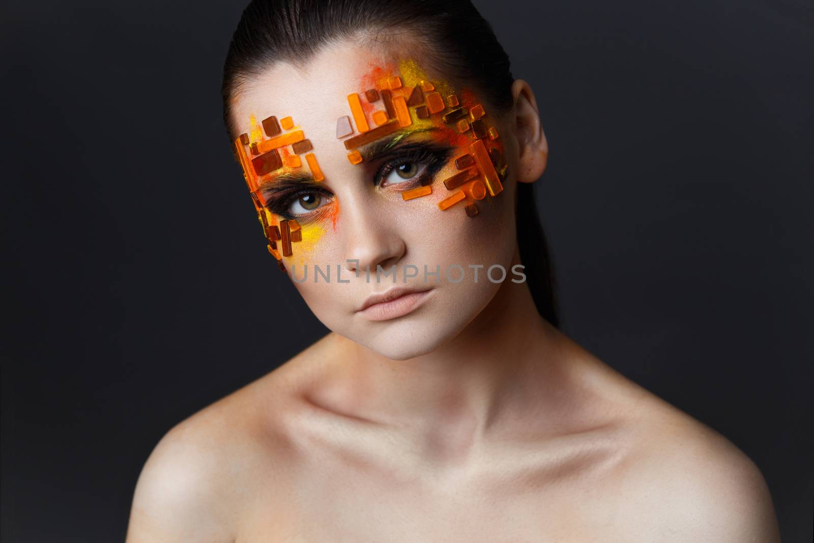 Portrait of a girl with an original make-up. Beauty close-up. Orange and red rhinestones on a face