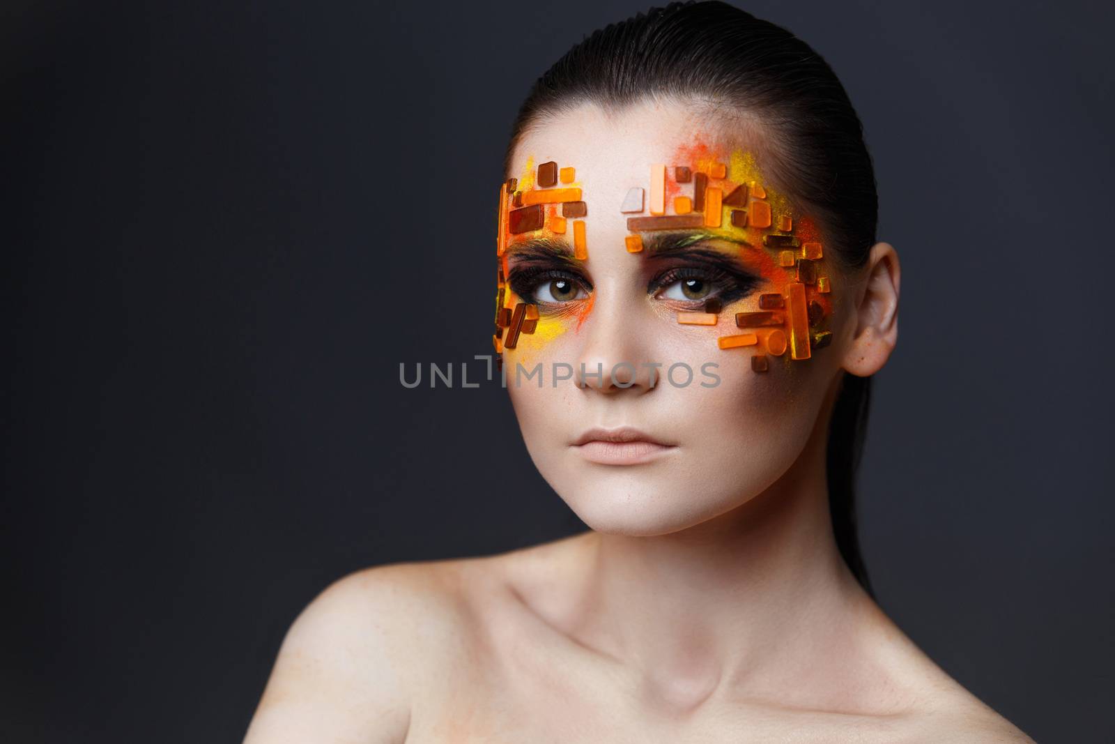 Portrait of a girl with an original make-up. Beauty close-up. Orange and red rhinestones on a face