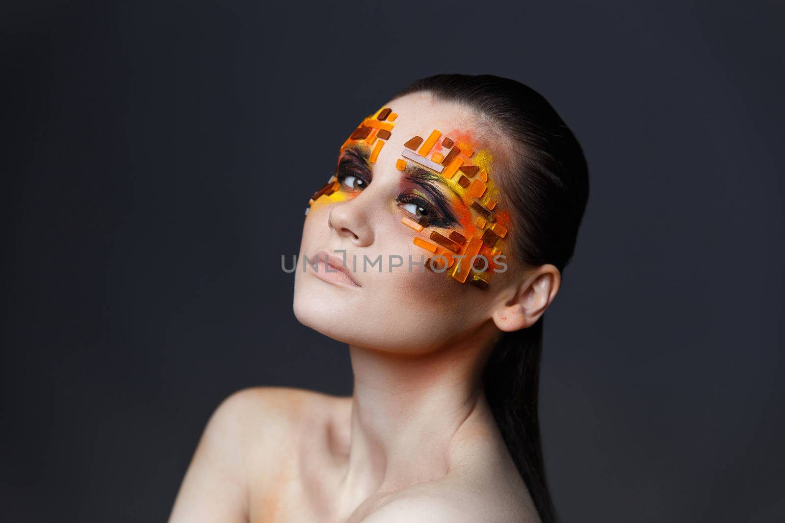 Portrait of a girl with an original make-up. Beauty close-up. Orange and red rhinestones on a face