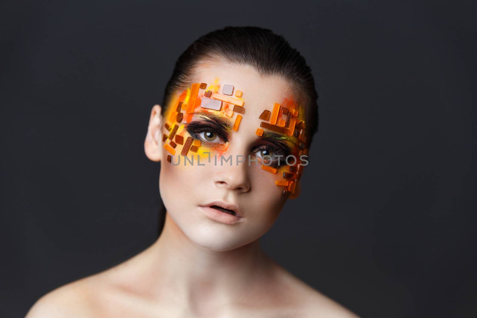 Portrait of a girl with an original make-up. Beauty close-up. Orange and red rhinestones on a face