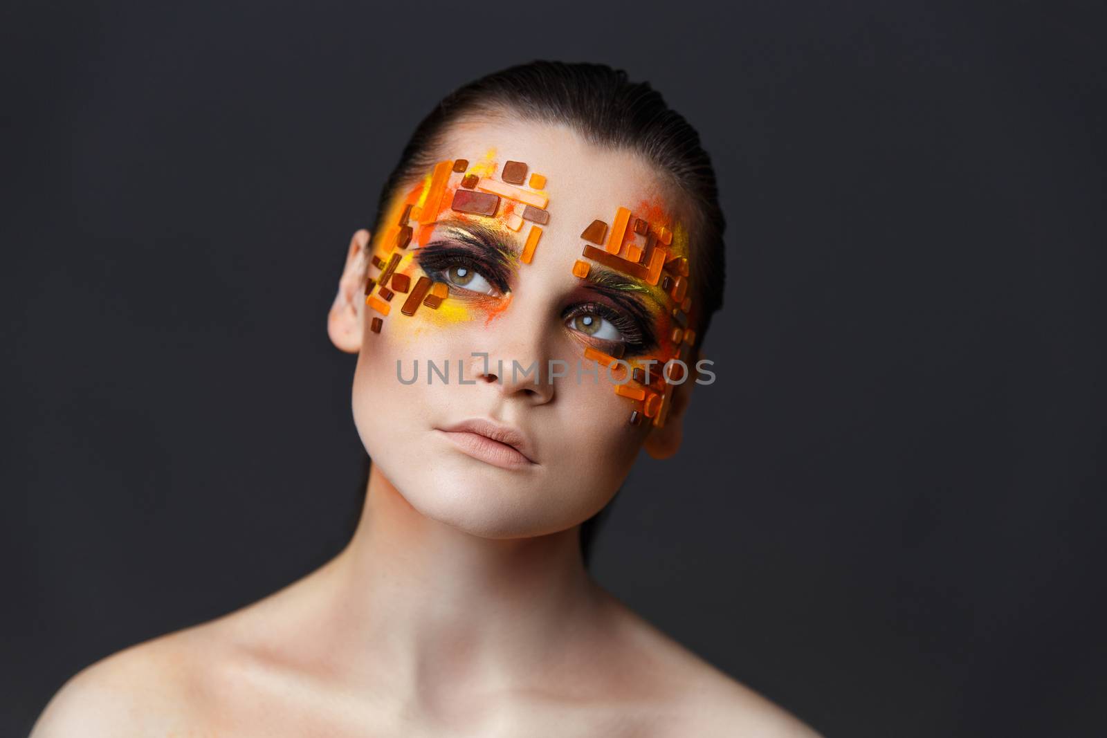 Portrait of a girl with an original make-up. Beauty close-up. Orange and red rhinestones on a face