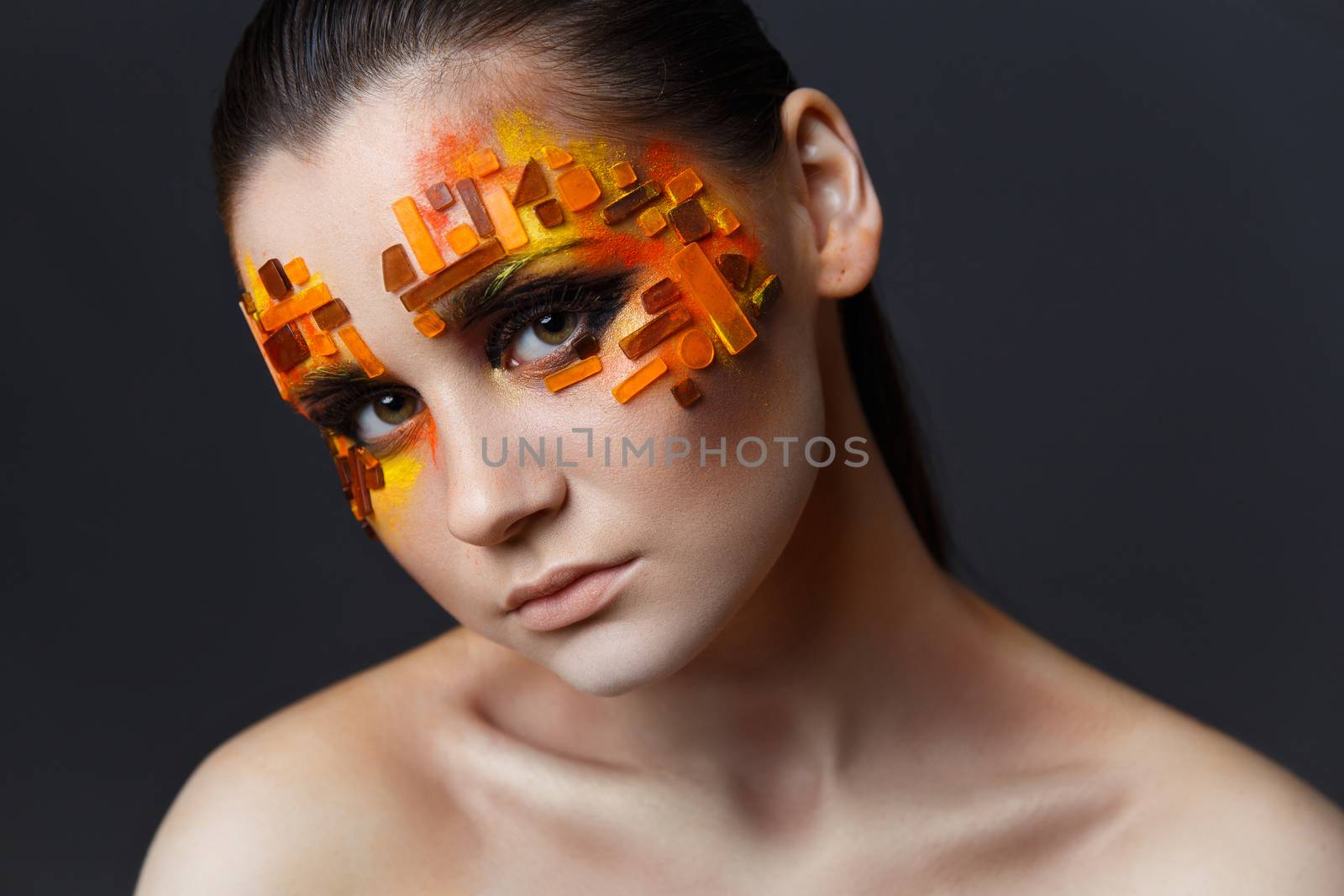 Portrait of a girl with an original make-up. Beauty close-up. Orange and red rhinestones on a face