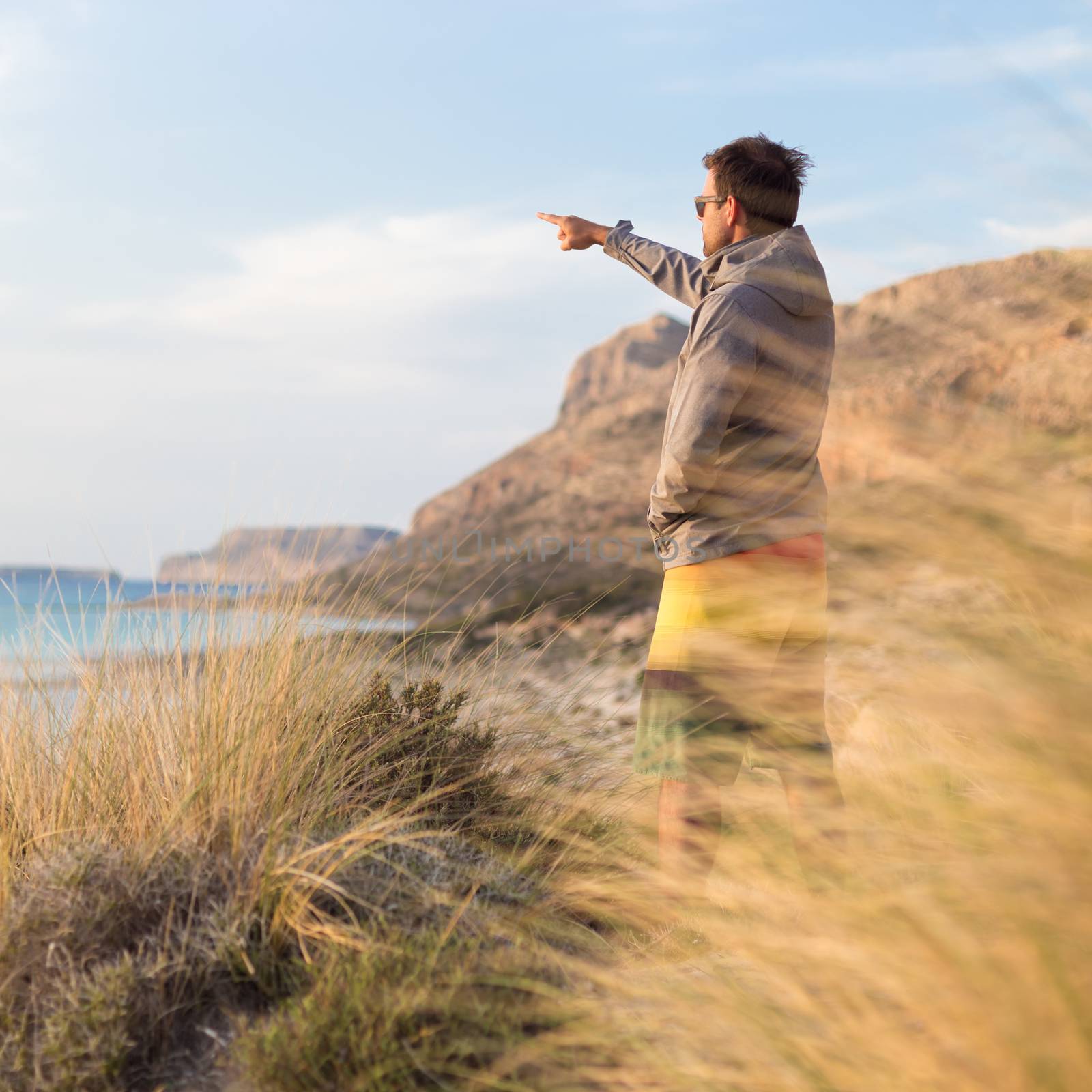 Sporty active man pointing hand on horizon, enjoying beauty of nature, freedom and life at beautiful landscape. Active lifestyle outdoors.