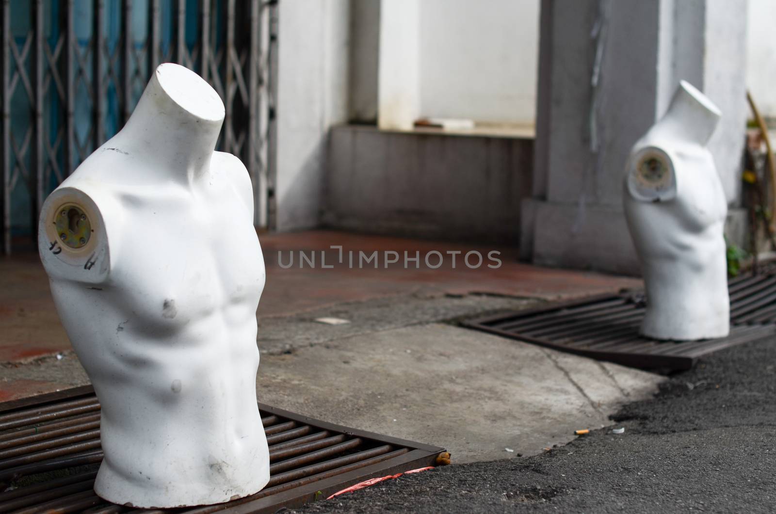 Torso male mannequin stand on the street near gutters
