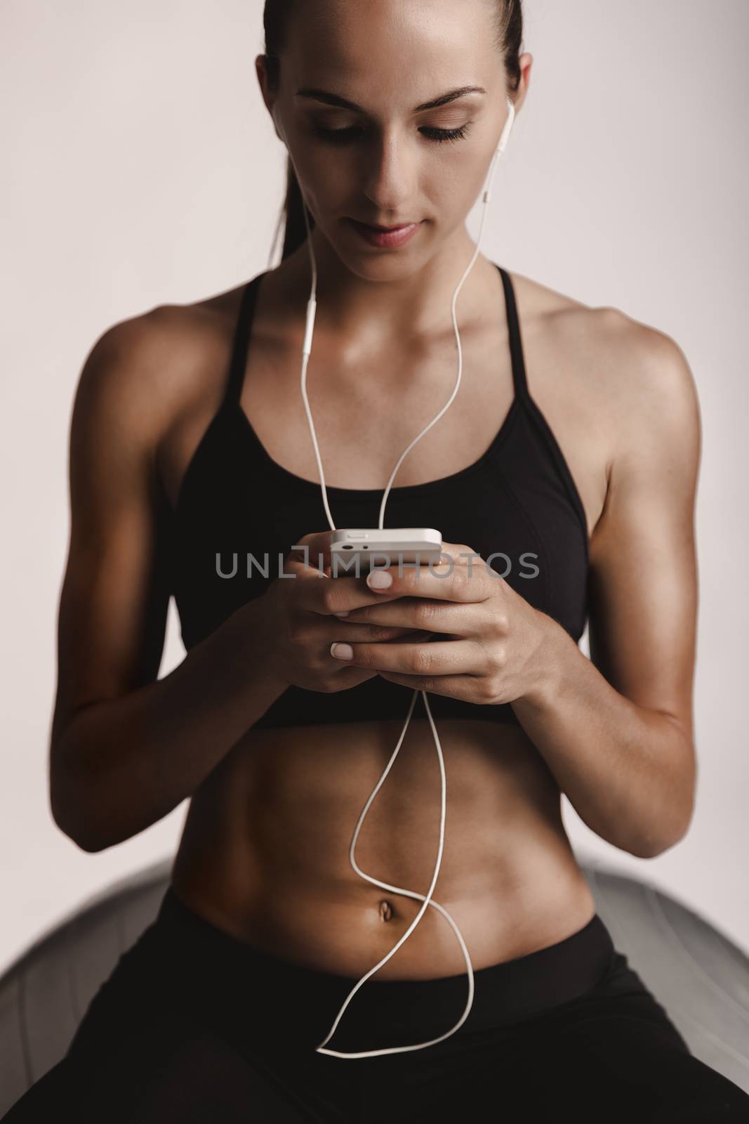 Shot of a beautiful young woman setting the music playlist for the workout.