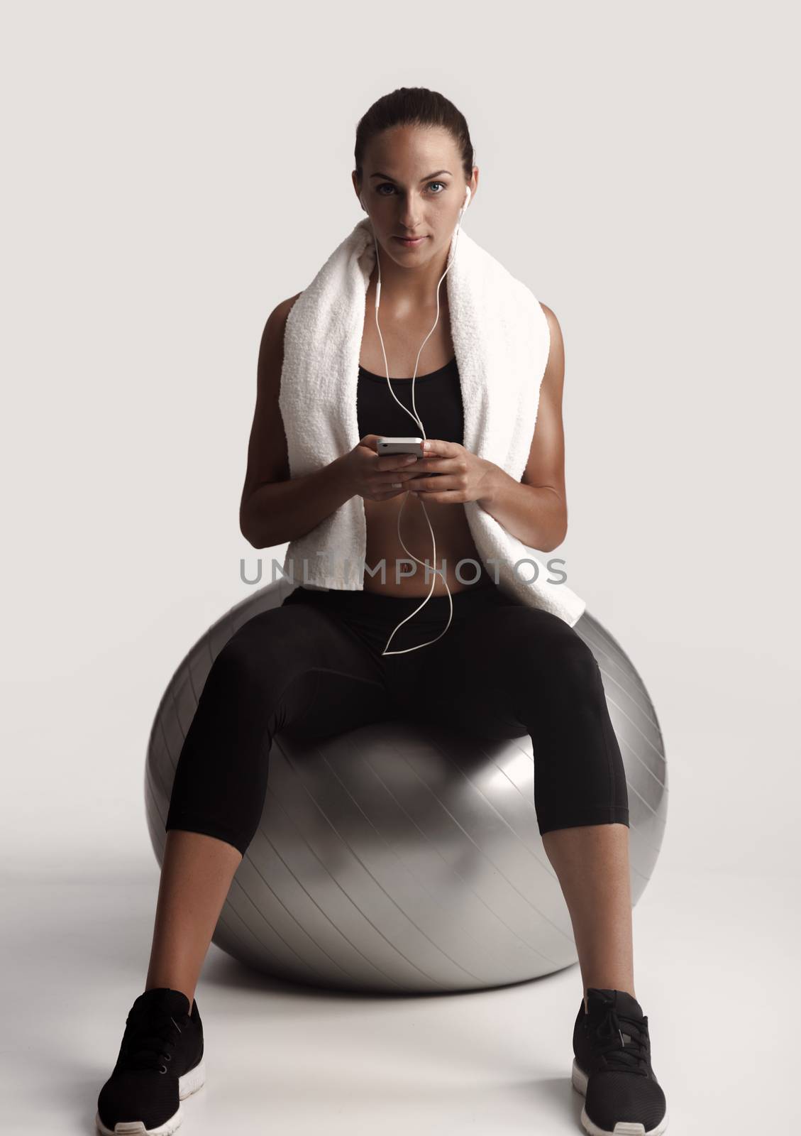 Shot of a beautiful young woman setting the music playlist for the workout.