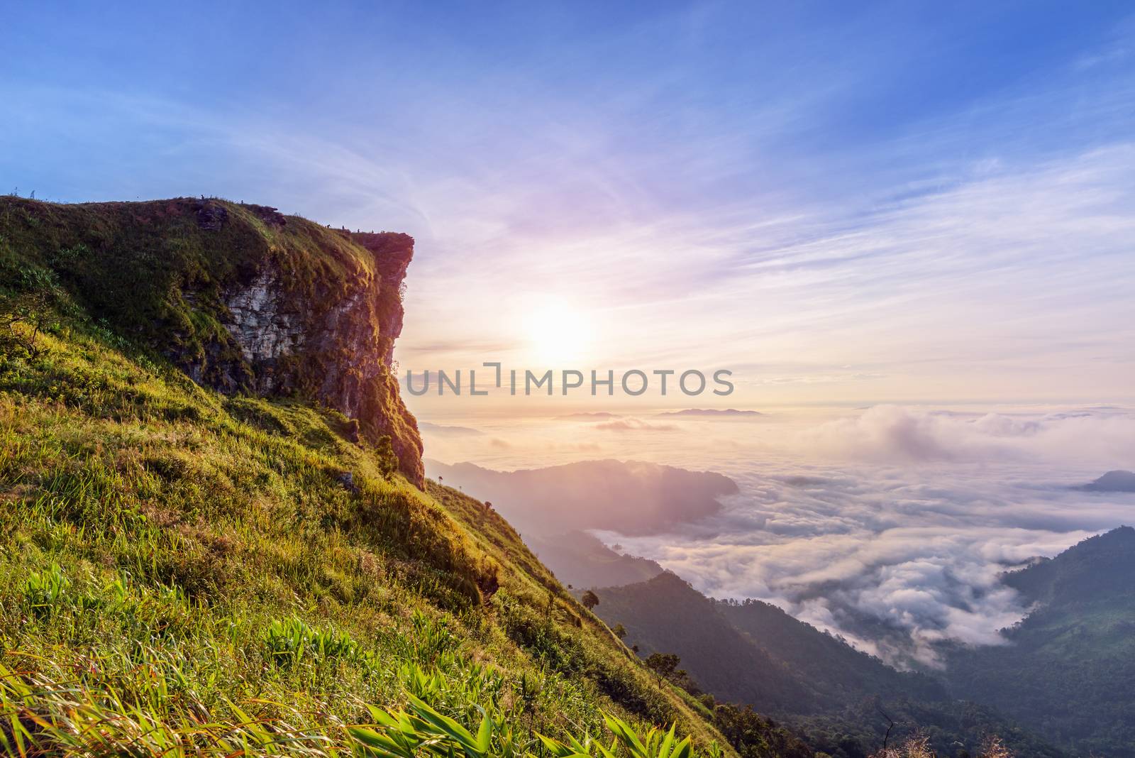 Beautiful landscape nature of sunrise on peak mountain with sun cloud fog and bright colors of sky in winter at Phu Chi Fa Forest Park is a famous tourist attraction of Chiang Rai Province, Thailand