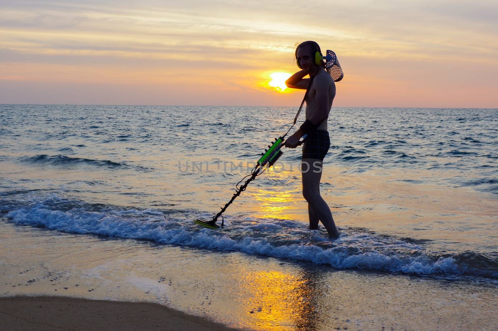 a treasure hunter with Metal detector on the beach