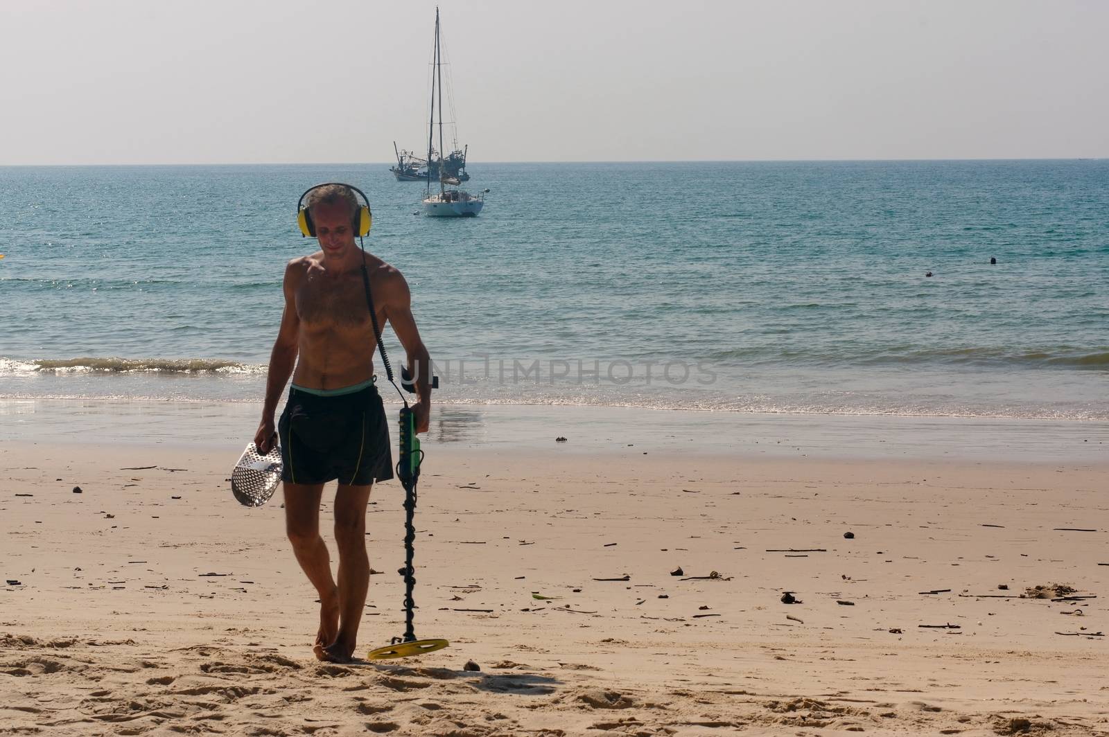 a treasure hunter with Metal detector on the beach