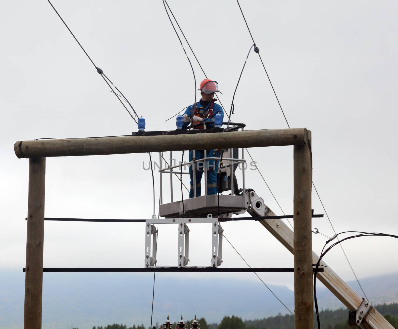 Electrician working at a power transmission line construction by AleksandrN
