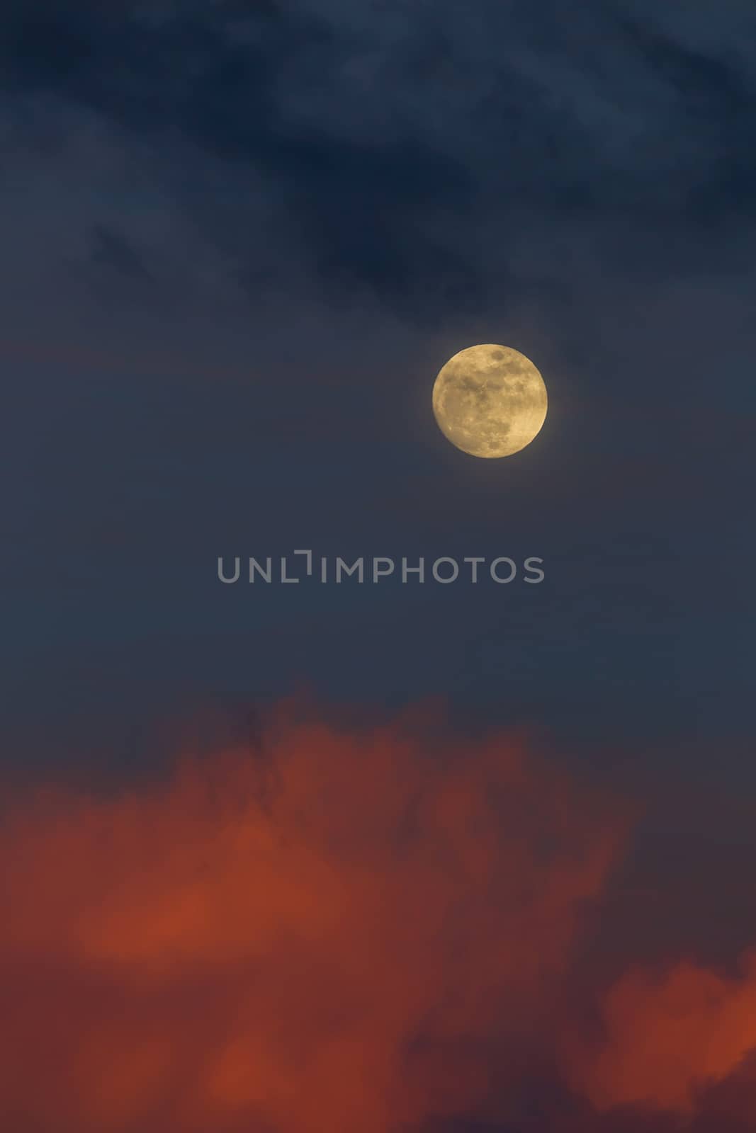 Moonrise in the East during sunset with pink clouds and blue sky