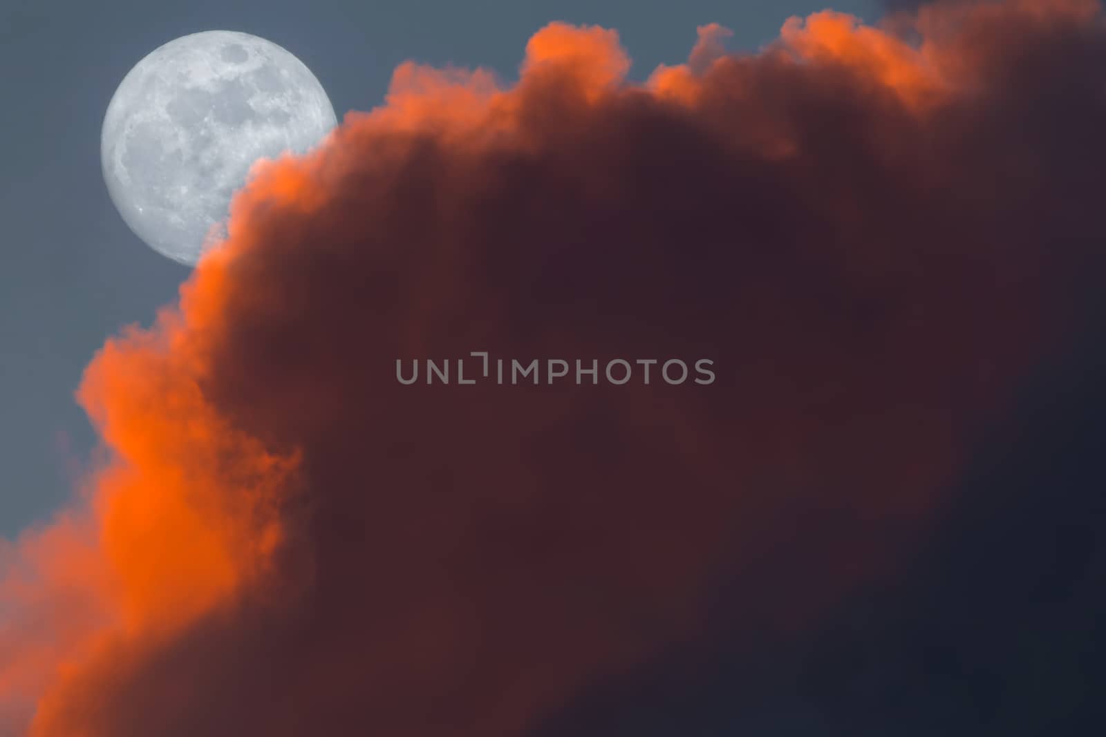 Full Snow Moon Rise peeking behind pink clouds during sunset