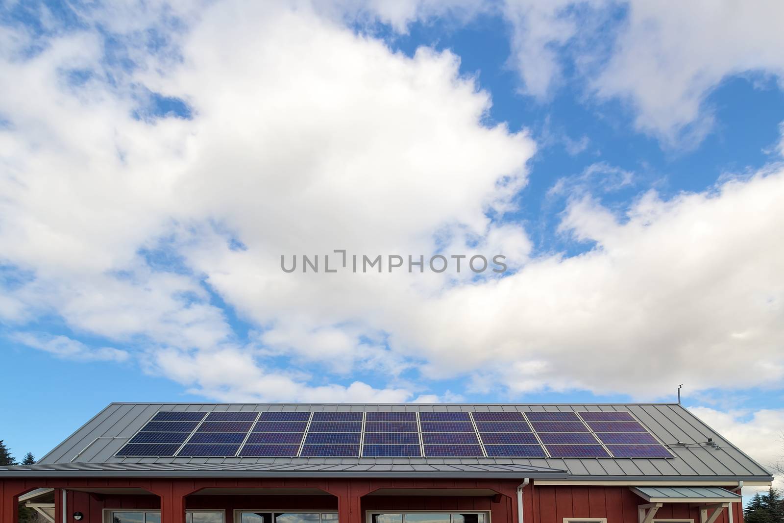 Solar Panels for generating eco-friendly electricity on the rooftop of house against white clouds and blue sky
