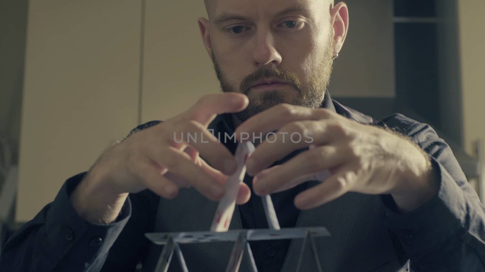 Portrait of a man building a house of a playing cards.