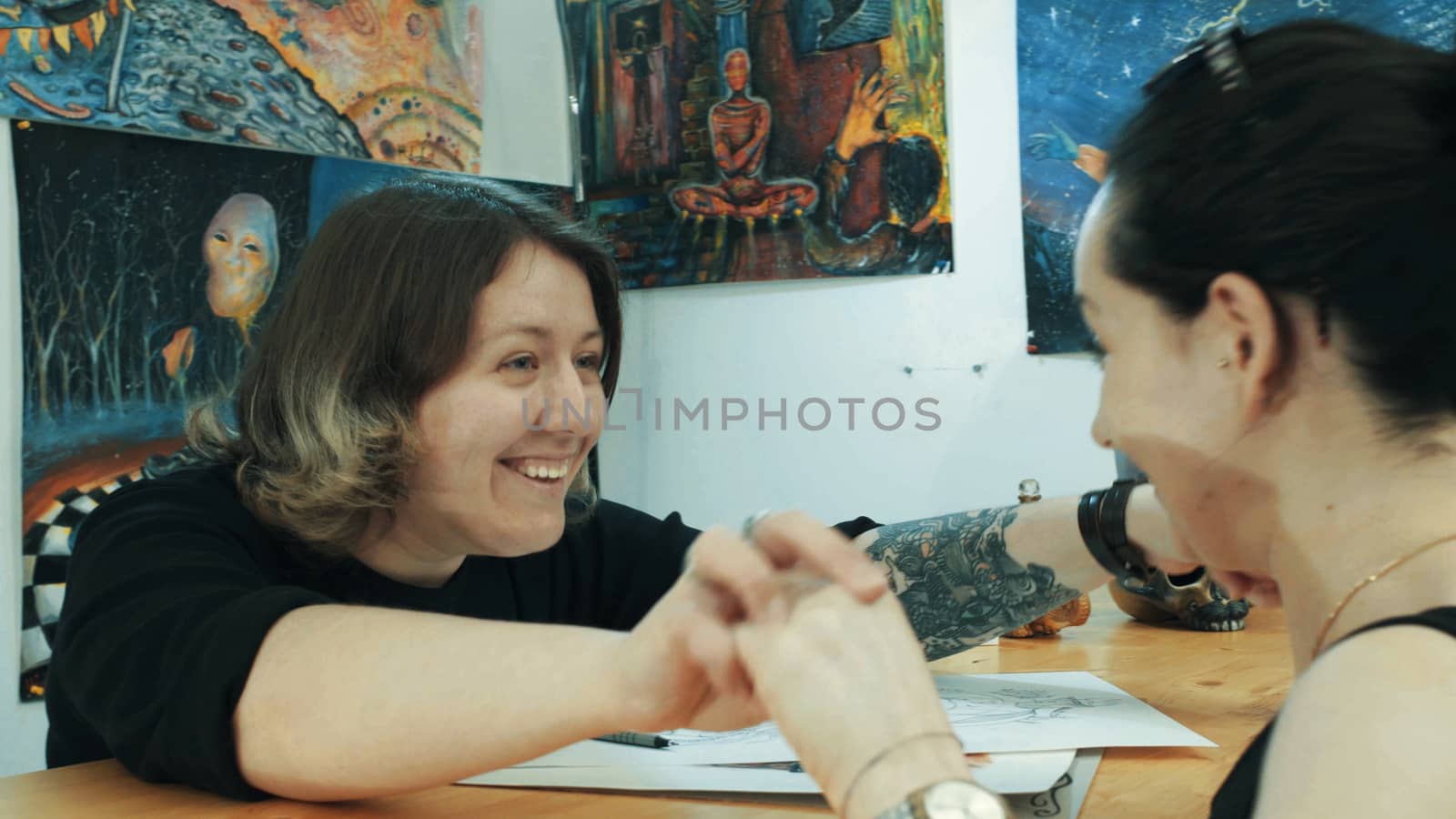 Portrait of two womans in tattoo salon. They are glad to see each other. Medium shot