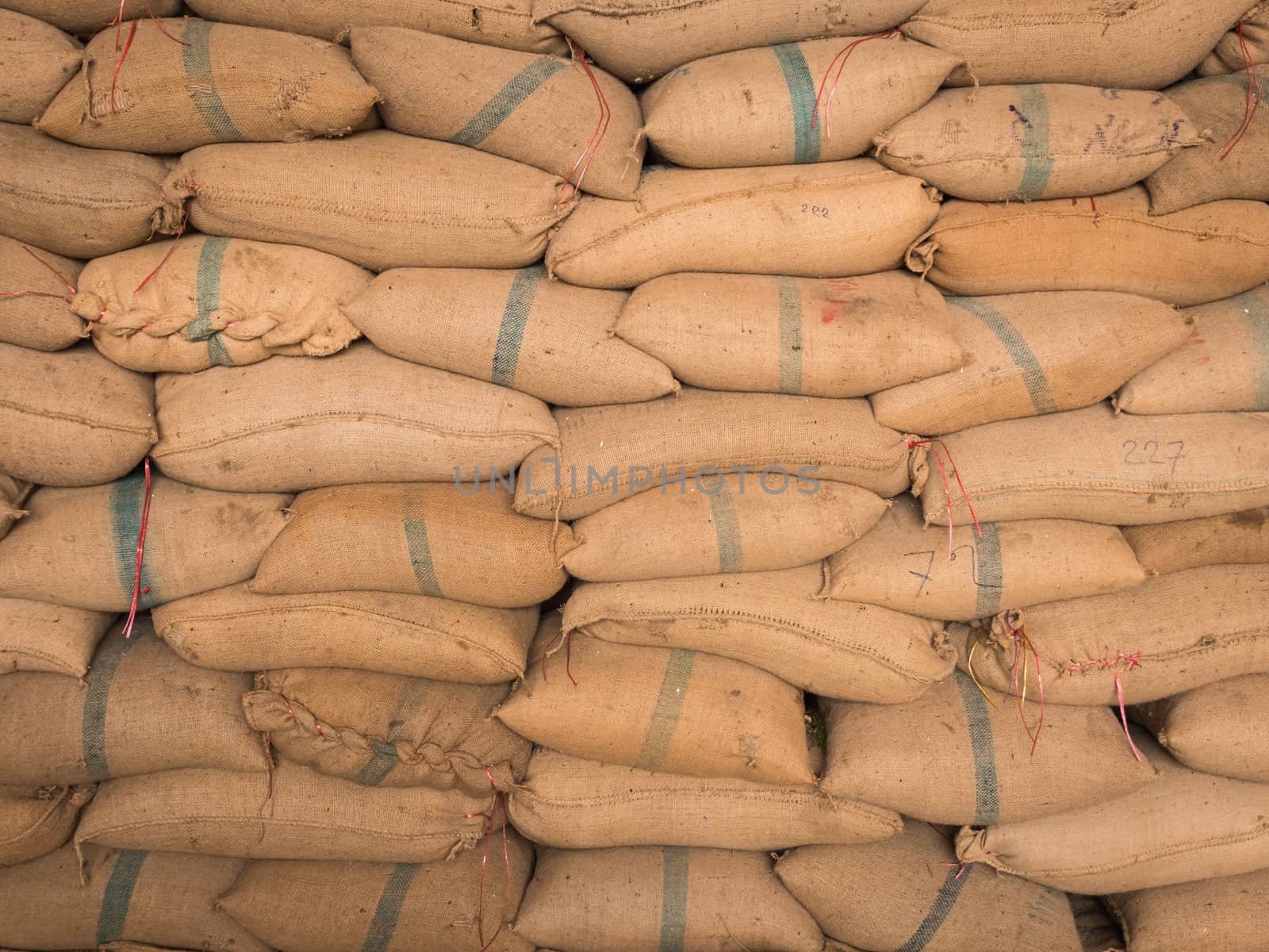 Old hemp sacks containing rice placed stacked in a row.