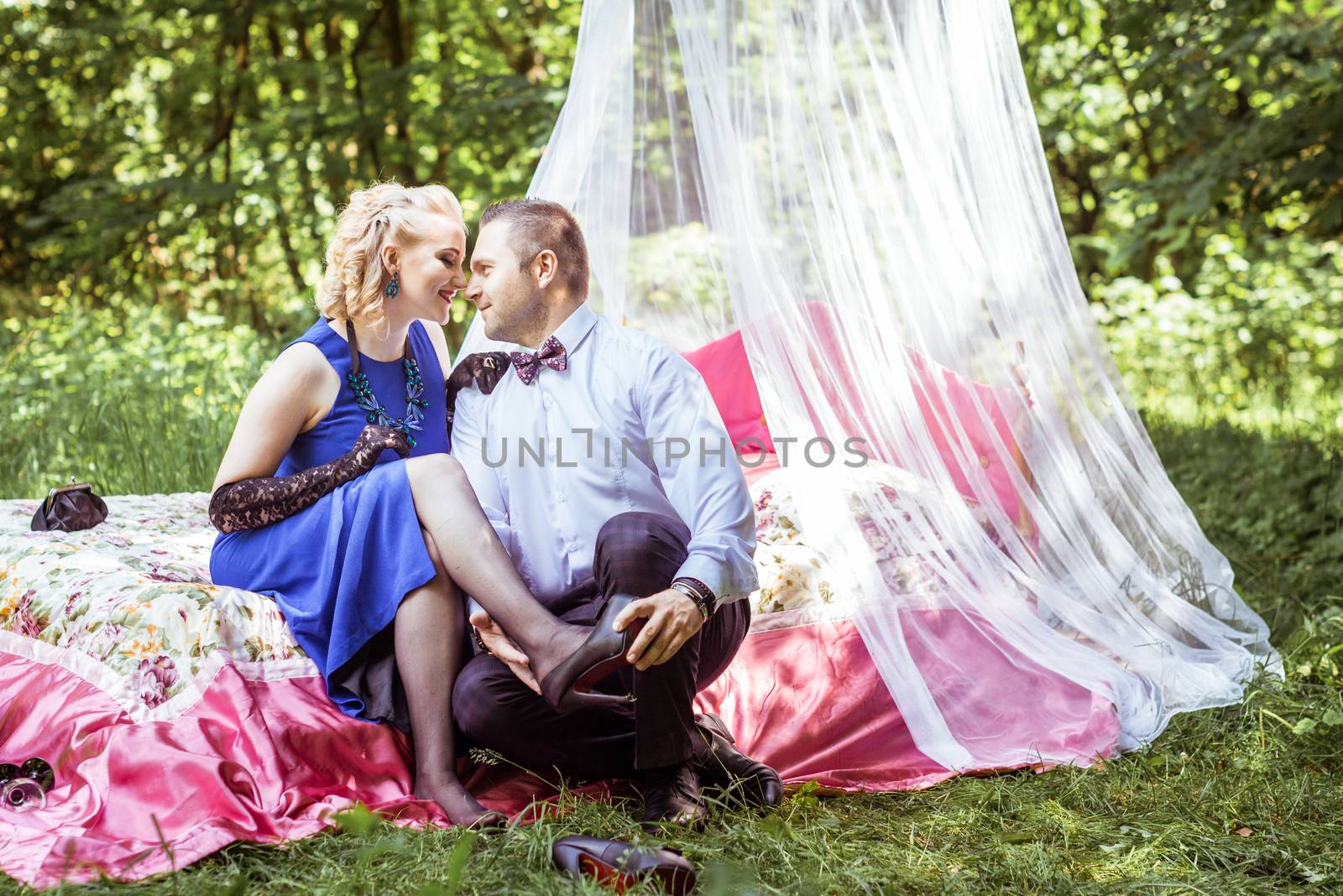 Man and woman sitting on the bed and looking at each other in the lawn. Man takes off shoes from women in Lviv, Ukraine.