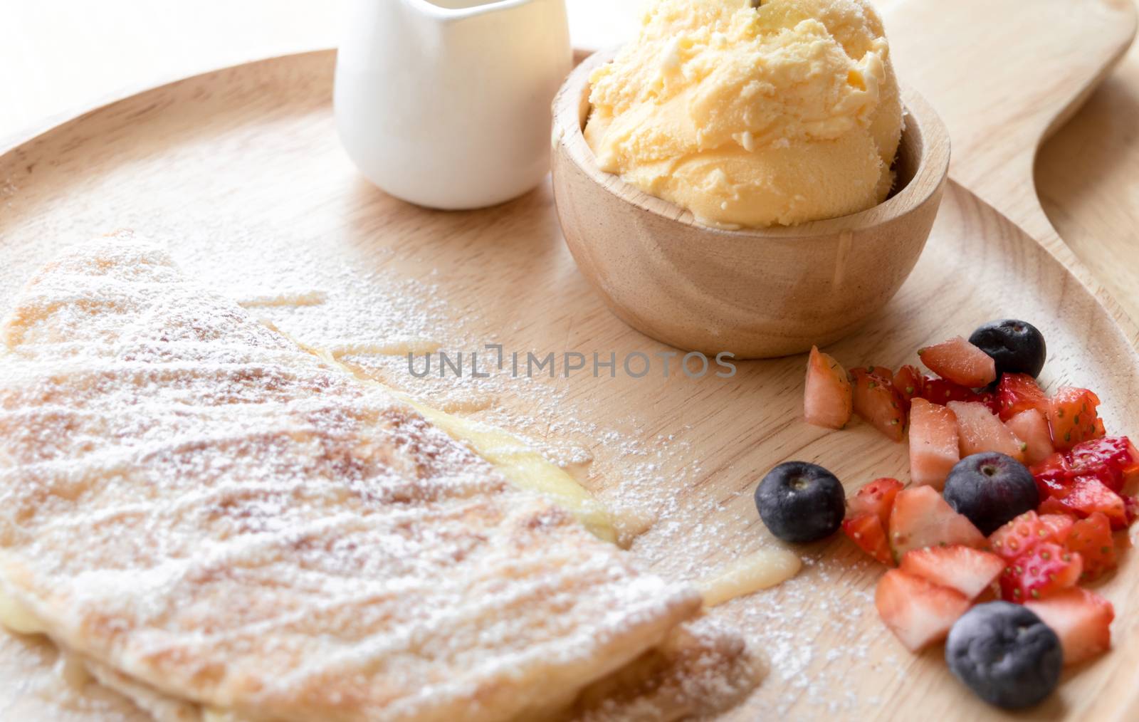 fresh dessert soft vanila roti with ice cream ,syrup ,strawberry and blueberry on plate in restaurant ,selective focus