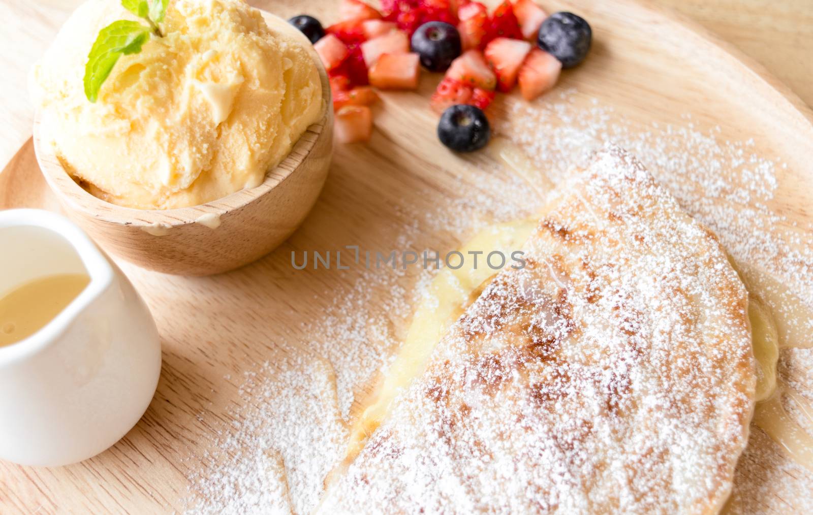 fresh dessert soft vanila roti with ice cream ,syrup ,strawberry and blueberry on plate in restaurant ,selective focus.