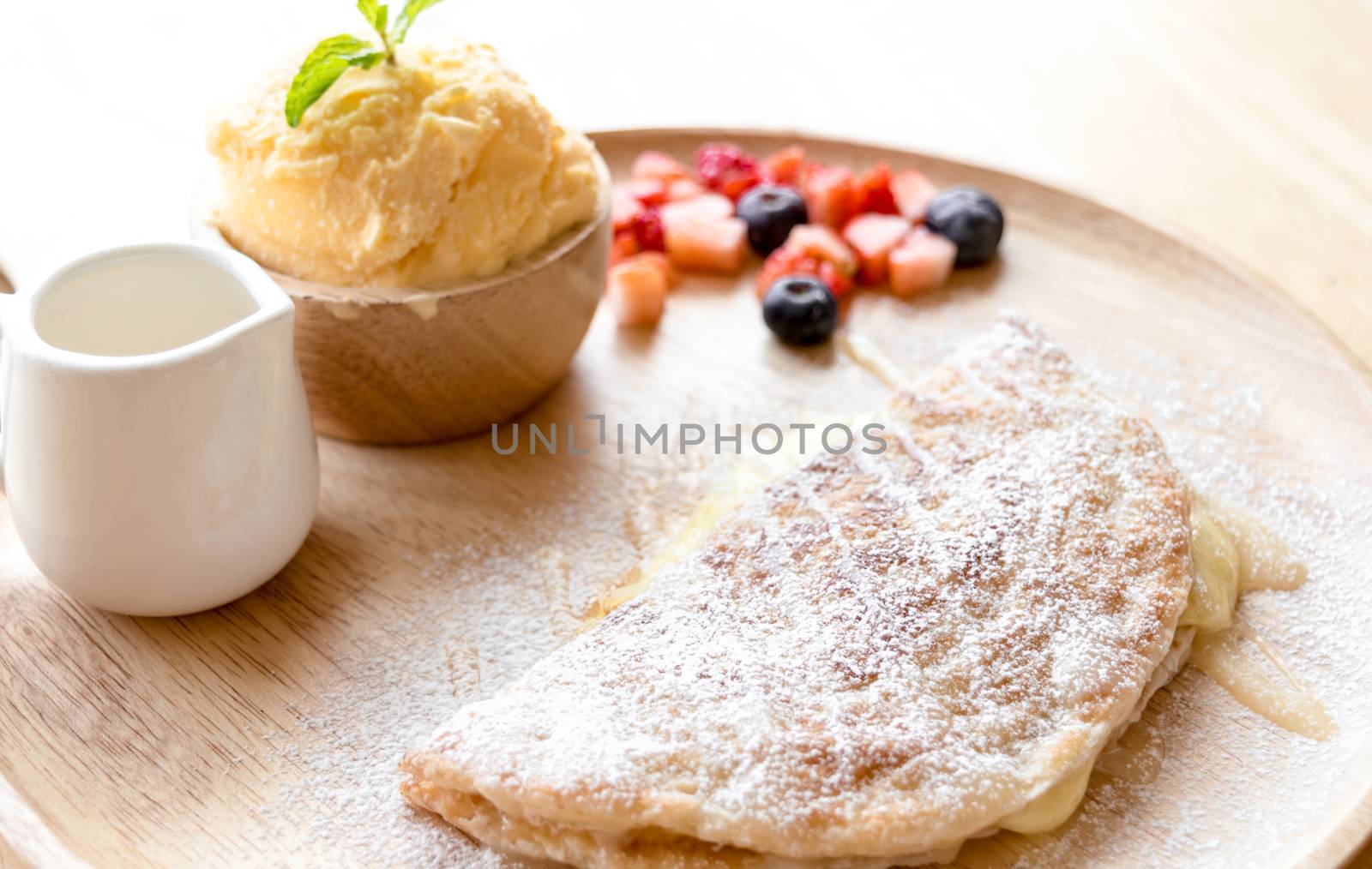 fresh dessert soft vanila roti with ice cream ,syrup ,strawberry and blueberry on plate in restaurant ,selective focus
