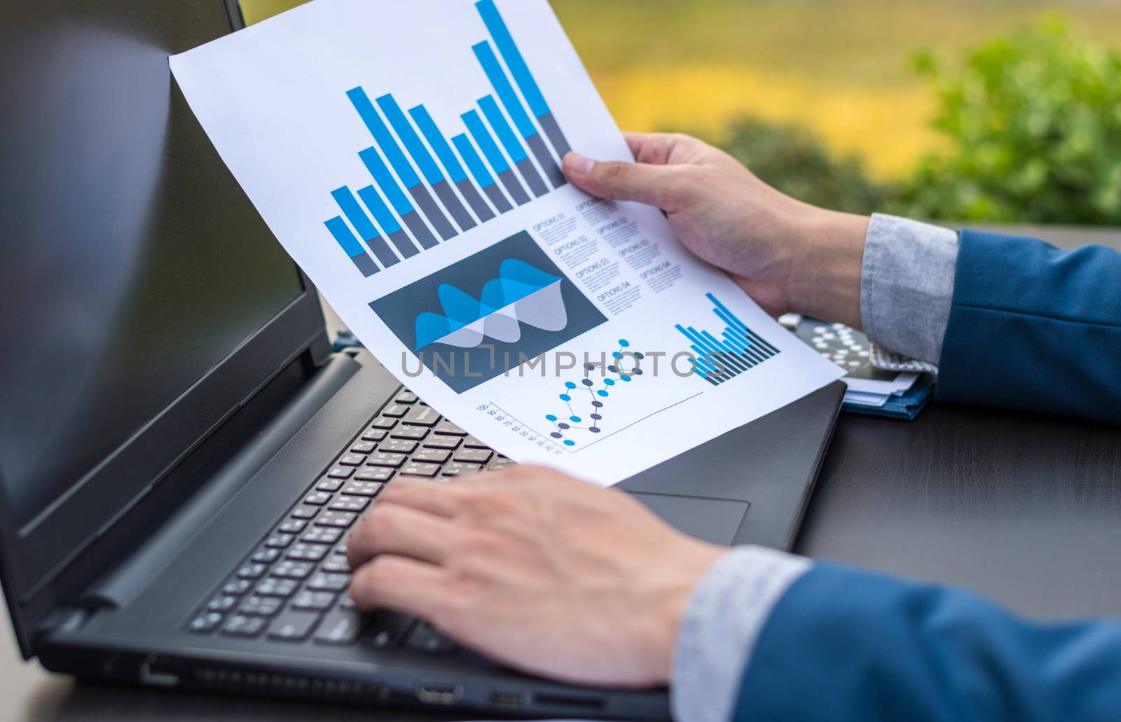 Handsome businessman wearing suit and using modern laptop outdoors and graph finance diagram
