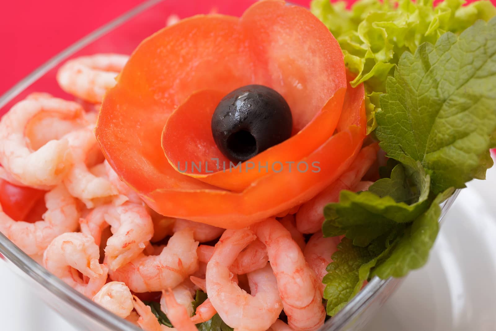 Seafood salad with shrimps and fresh vegetables, on a serving table. On a red tablecloth close-up. View from above