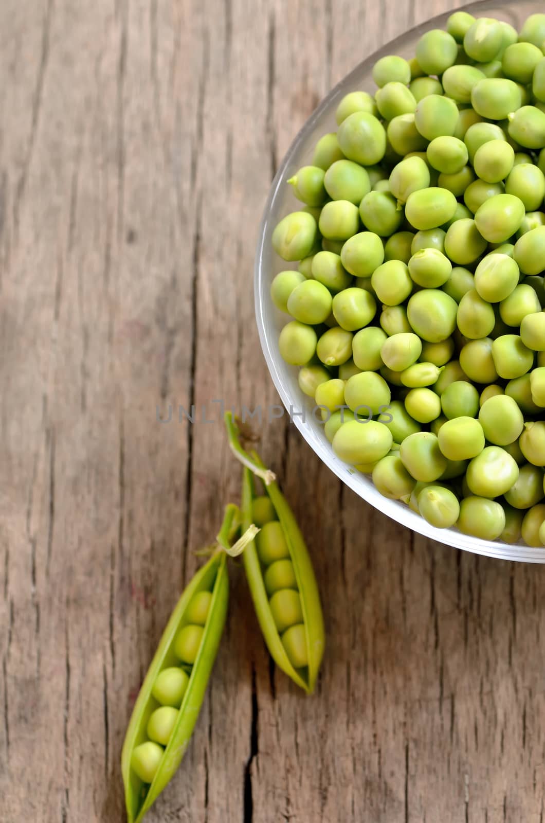 Green peas in a bowl on a wooden background