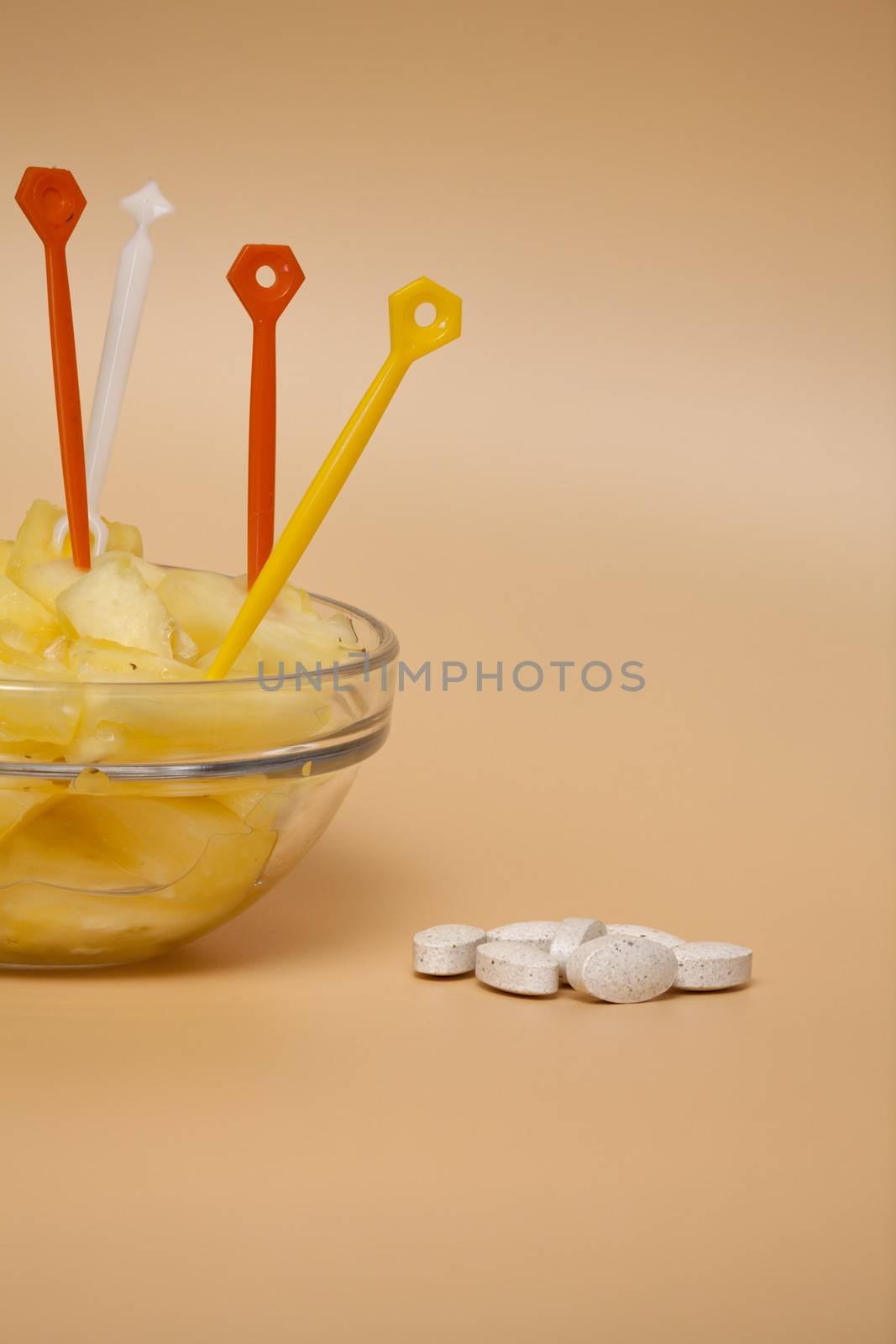 cup filled with pineapple slices handful of pills concept of healthy nutrition and prevention medicine