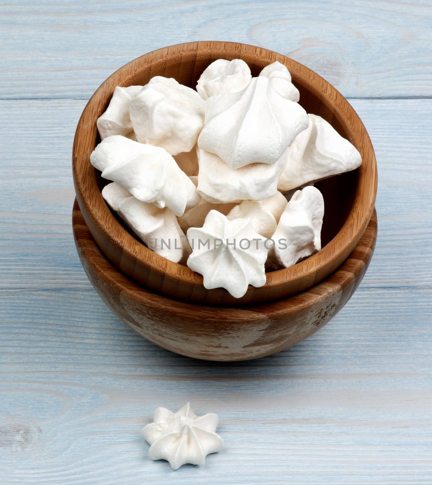 Arrangement of Vanilla Meringues Cakes In Wooden Bowls closeup on Blue Wooden Background