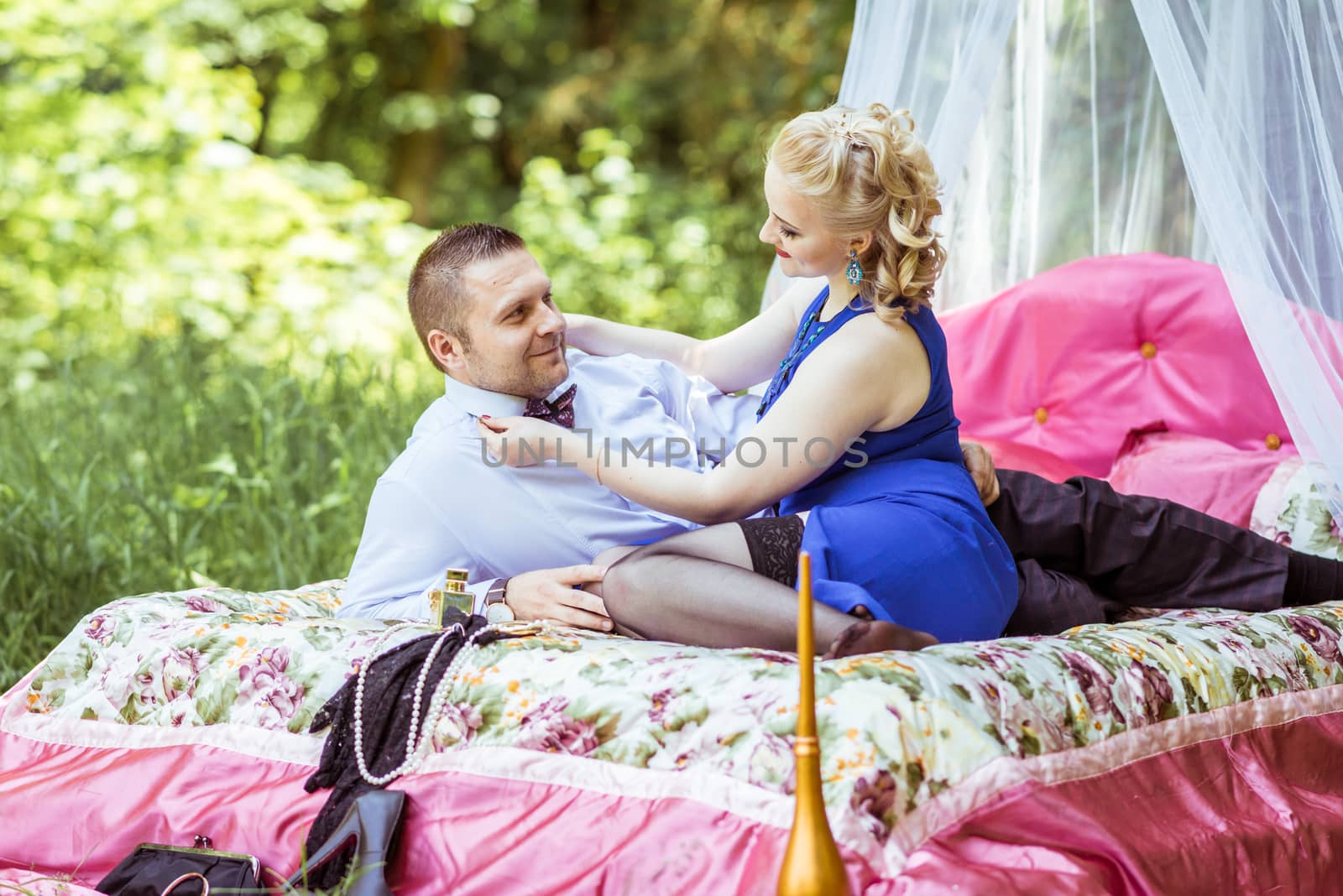 Man and woman sitting on the bed in the lawn and woman undressing man in Lviv, Ukraine.