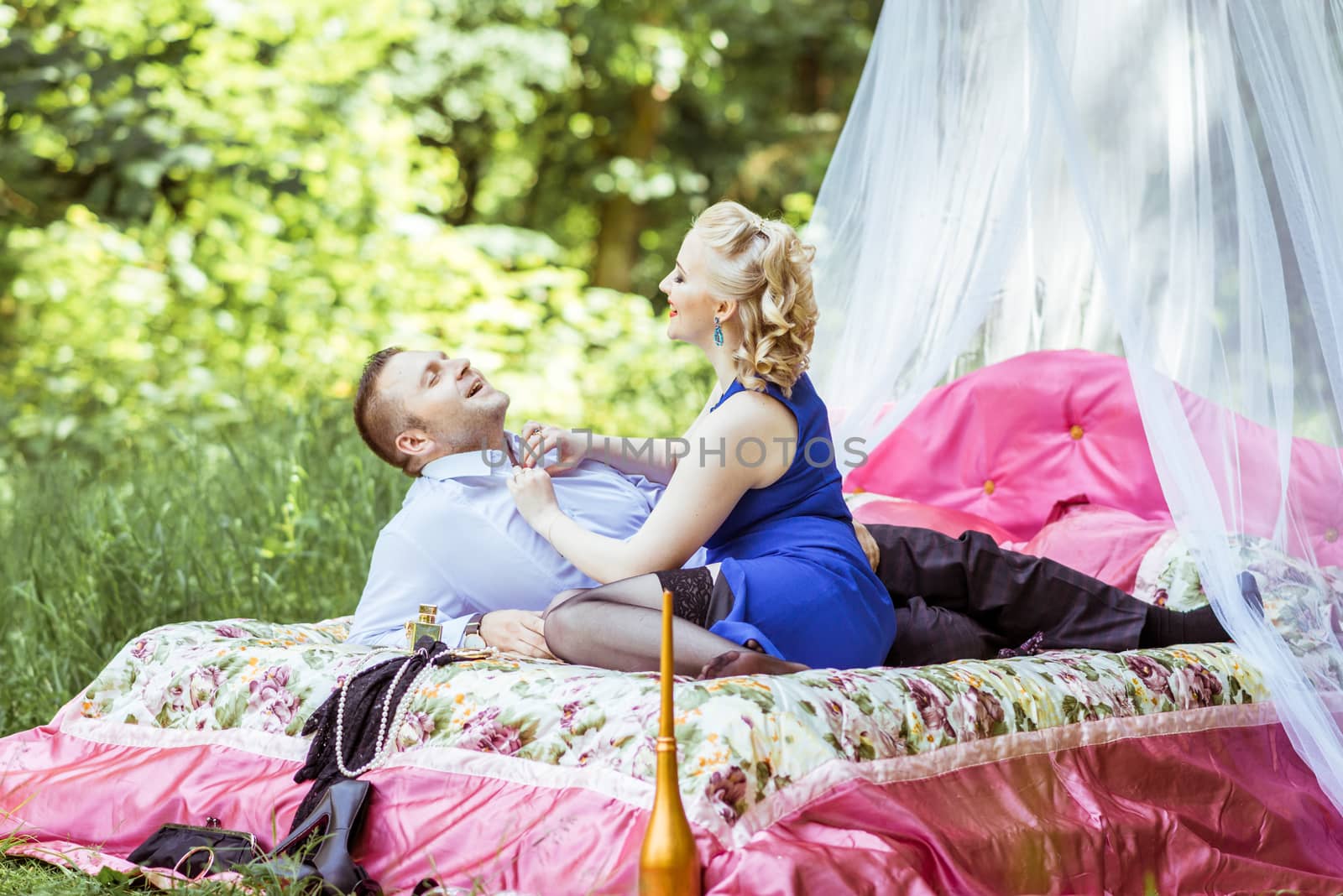 Man and woman sitting on the bed in the lawn and woman undressing man in Lviv, Ukraine.