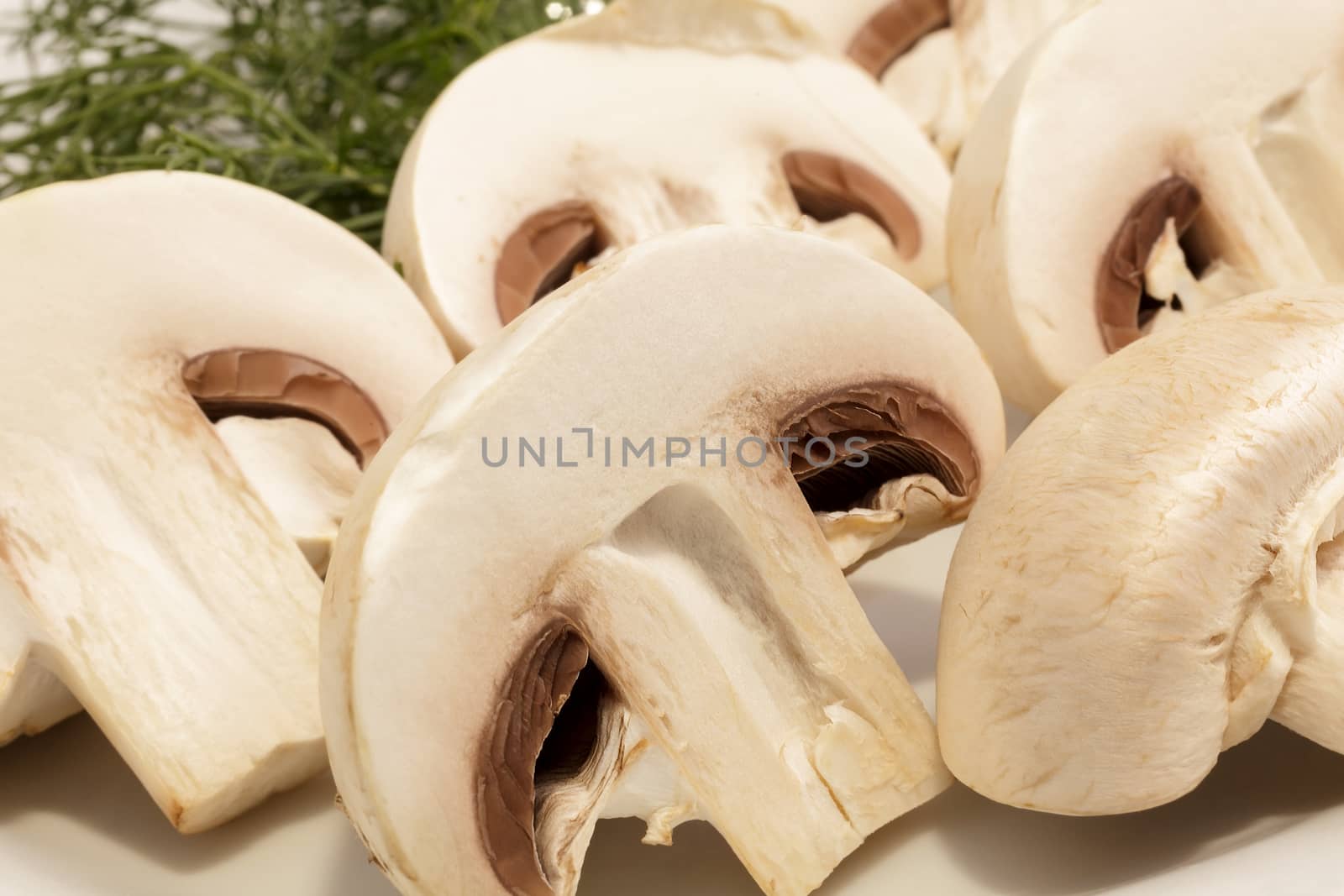 Cut champignons on a plate with greens. Close-up