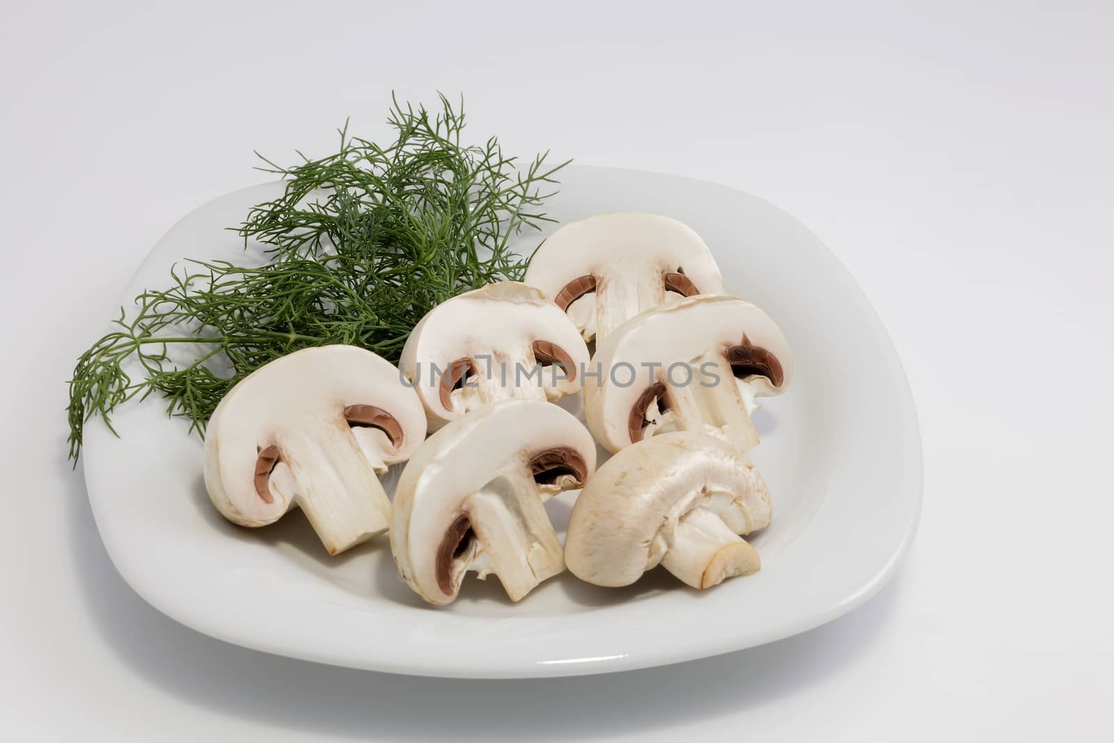 Cut champignons on a plate with greens. Close-up