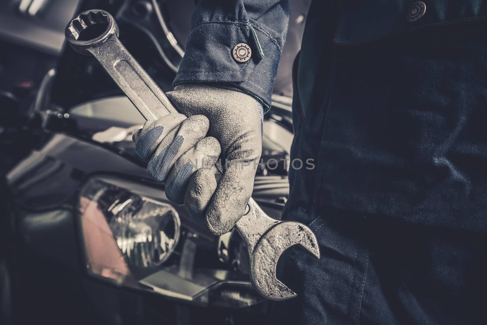 Fixing the Car Concept. Mechanic with Large Wrench is About To Start His Car Maintenance and Fix Work.
