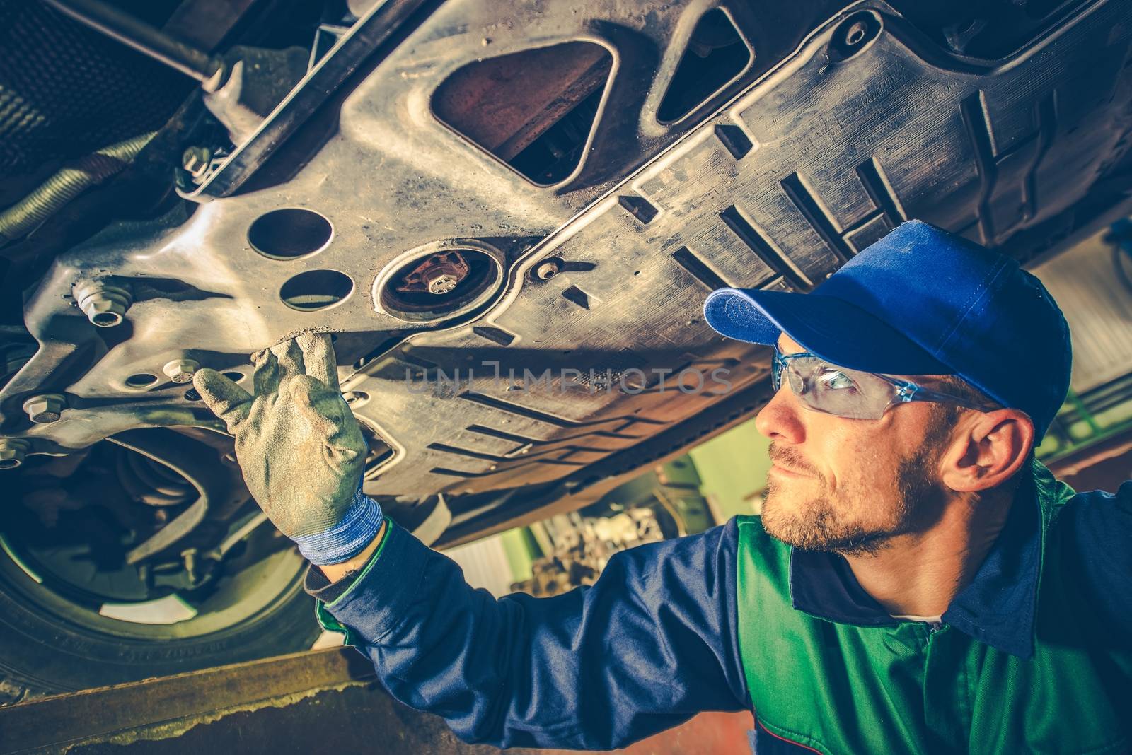 Caucasian Mechanic Fixing the Car. Mechanic Working Under the Vehicle.