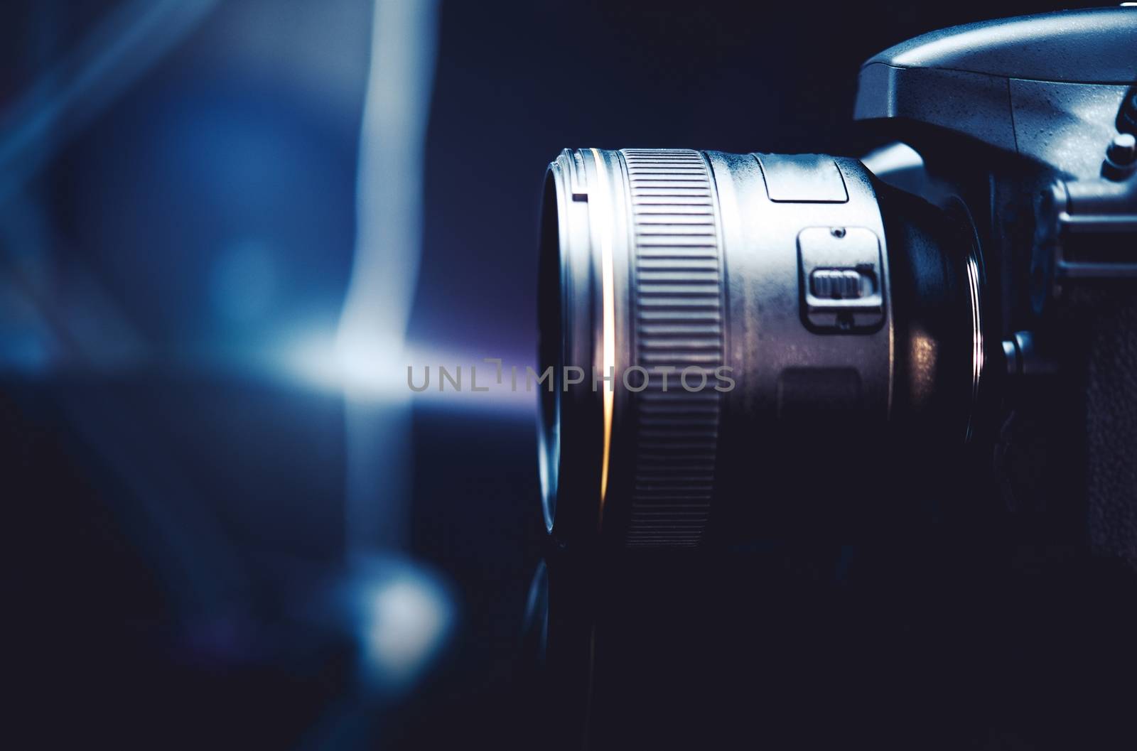 Digital Camera and the Photography Concept Photo. Dark Blue Color Grading with Little of Light. Camera Side View.