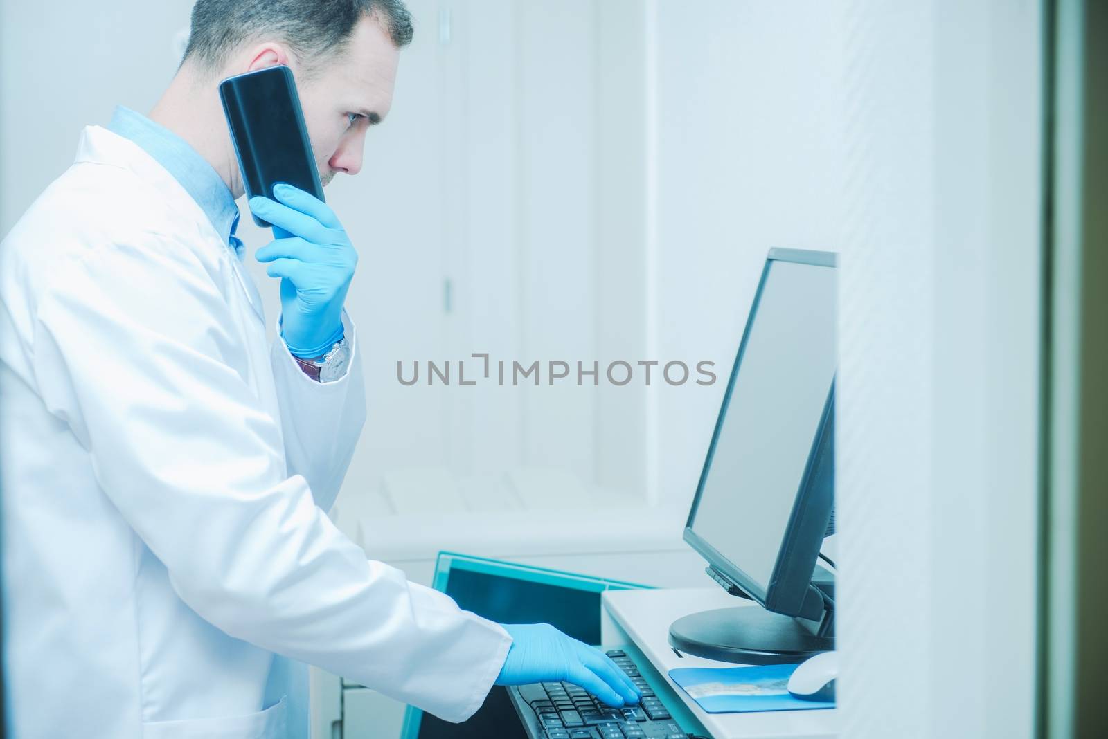 Doctor Consulting Results of Patient Testing While Staying in the Room in Front of His Office Computer and Talking by Phone. Caucasian Doctor.